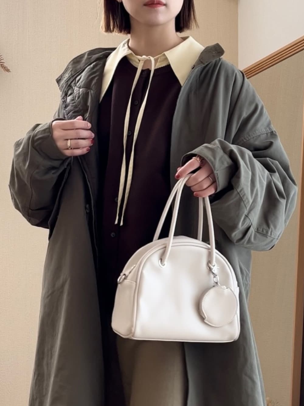 グリーン系のモッズコート、ブラウン系のカーディガン/ボレロ、ベージュ系のスカートを着用したレディースの冬コーディネートの4枚目の写真