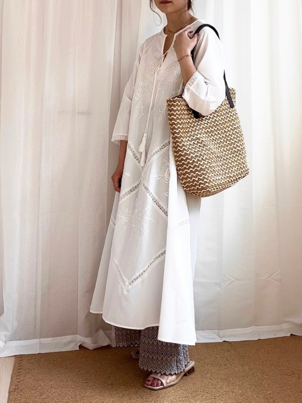 ホワイト系のワンピース、ベージュ系のかごバッグ、ベージュ系のサンダルを着用したレディースの夏コーディネートの2枚目の写真
