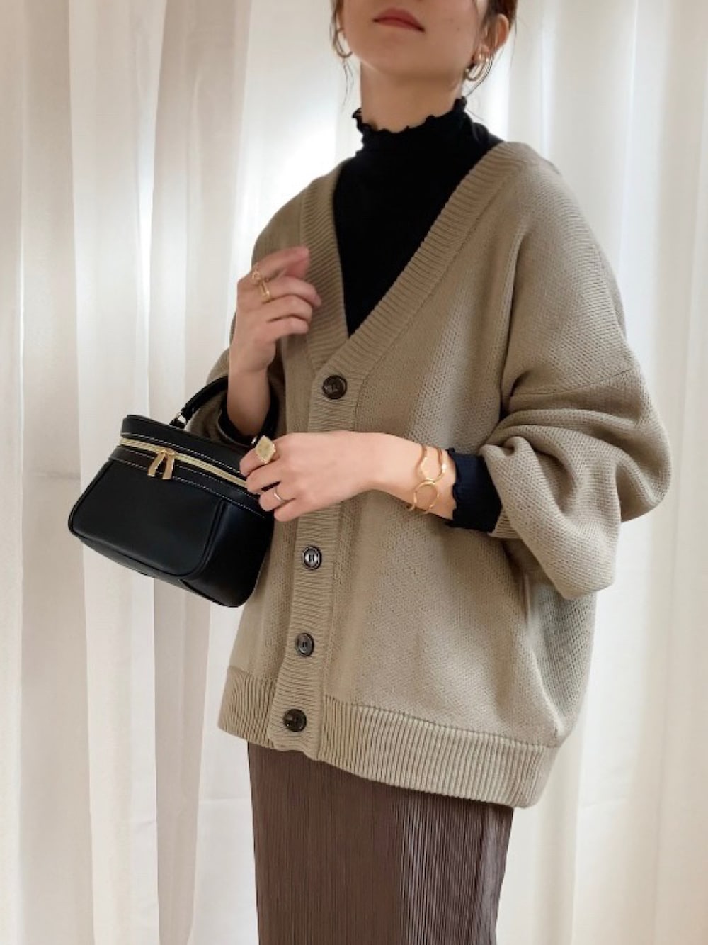 ベージュ系のカーディガン/ボレロ、ブラウン系のスカート、ブラック系のバッグを着用したレディースの冬コーディネートの2枚目の写真