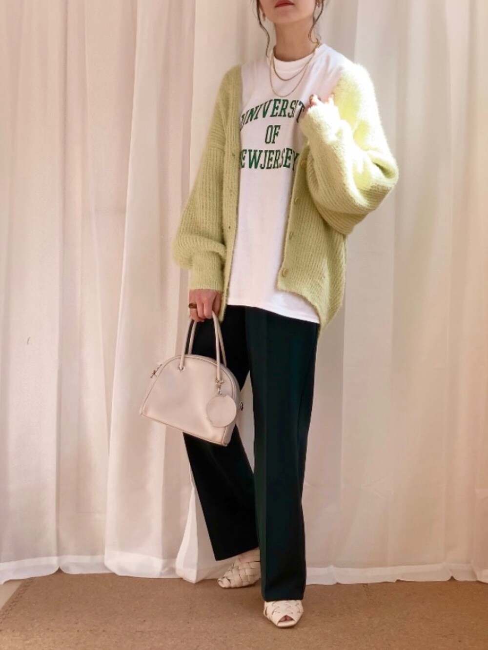 ホワイト系のTシャツ/カットソー、グリーン系のカーディガン/ボレロ、グリーン系のスラックスを着用したレディースの春コーディネートの2枚目の写真
