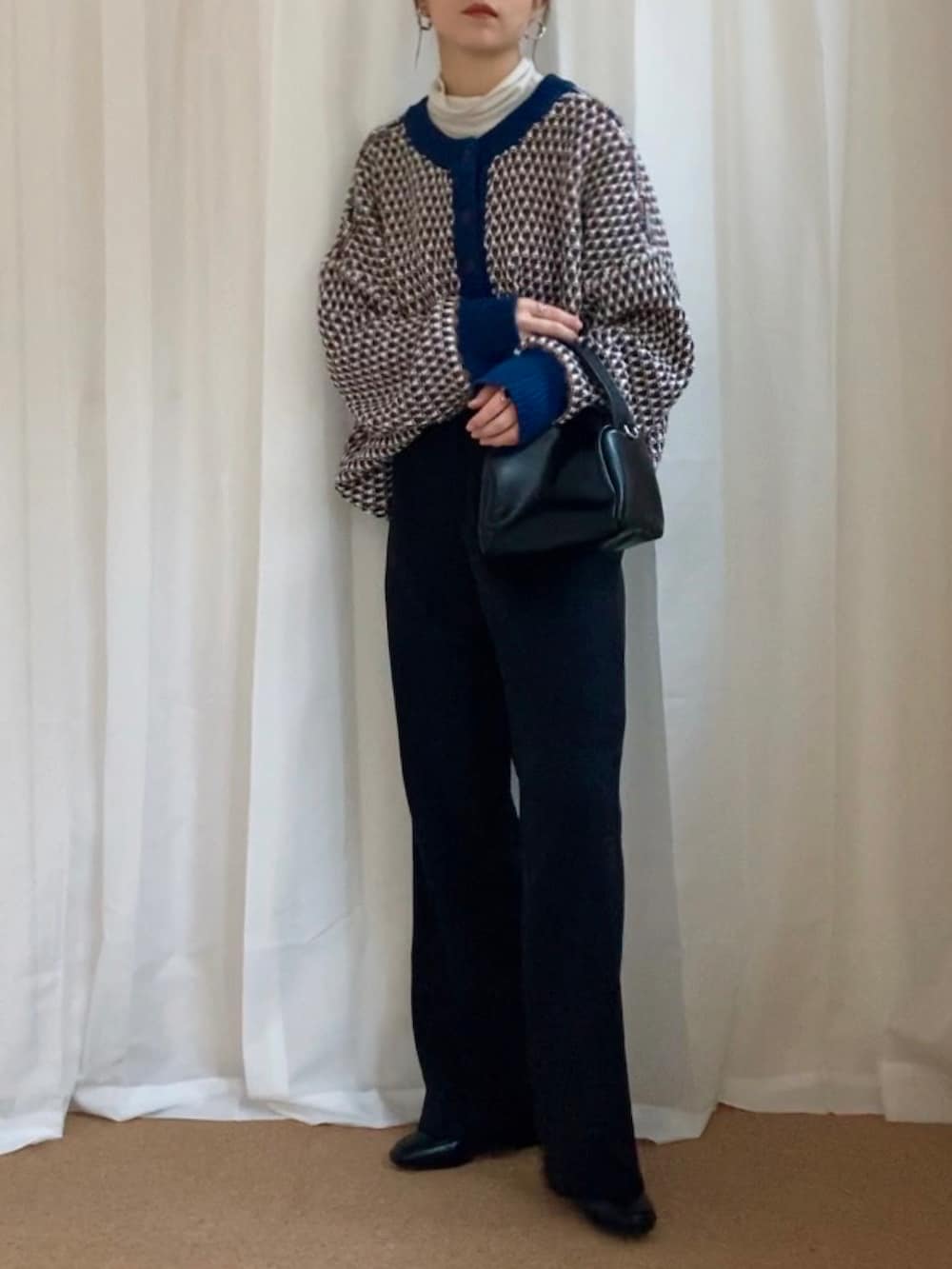 ブルー系のニット/セーター、ブラック系のスラックス、ブラック系のショルダーバッグを着用したレディースの冬コーディネートの3枚目の写真