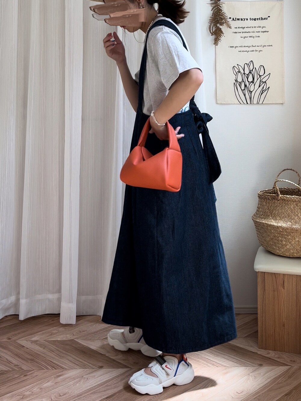 ベージュ系のTシャツ/カットソー、ブルー系のジャンパースカート、オレンジ系のハンドバッグを着用したレディースの夏コーディネートの4枚目の写真