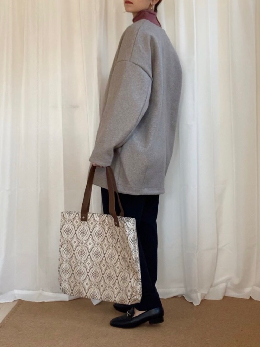 ベージュ系のノーカラーコート、ピンク系のニット/セーター、ベージュ系のトートバッグを着用したレディースの冬コーディネートの4枚目の写真