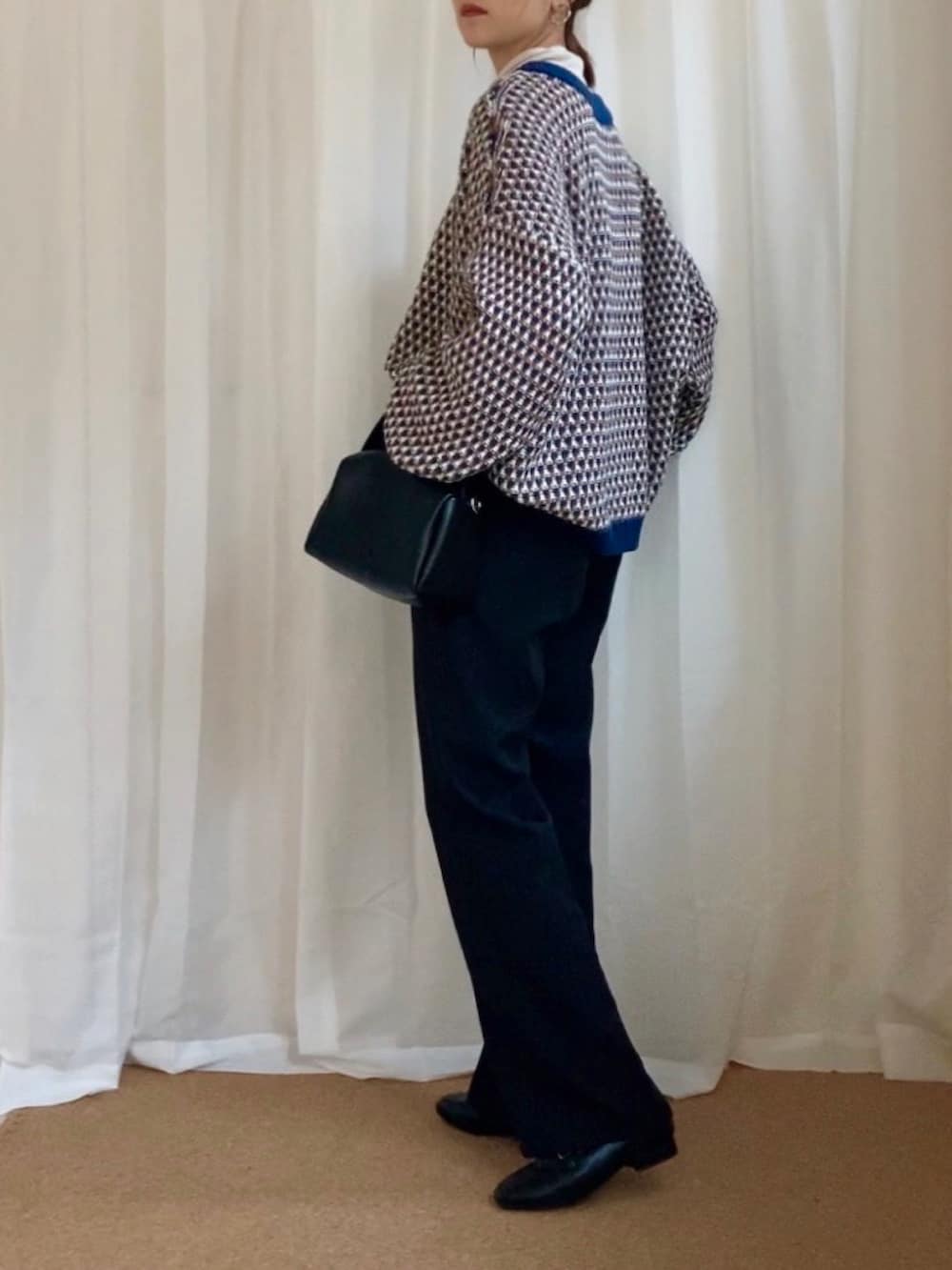 ブルー系のニット/セーター、ブラック系のスラックス、ブラック系のショルダーバッグを着用したレディースの冬コーディネートの2枚目の写真