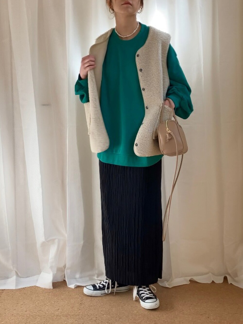グリーン系のスウェット、ベージュ系のベスト、ブラック系のスカートを着用したレディースの冬コーディネートの2枚目の写真