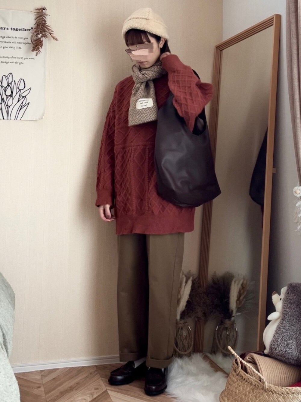 オレンジ系のニット/セーター、グリーン系のチノパンツ、ブラウン系のトートバッグを着用したレディースの冬コーディネートの2枚目の写真