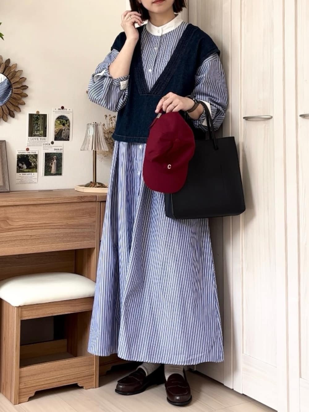 ブルー系のシャツワンピース、ブルー系のベスト、ブラック系のトートバッグを着用したレディースの春コーディネートの3枚目の写真