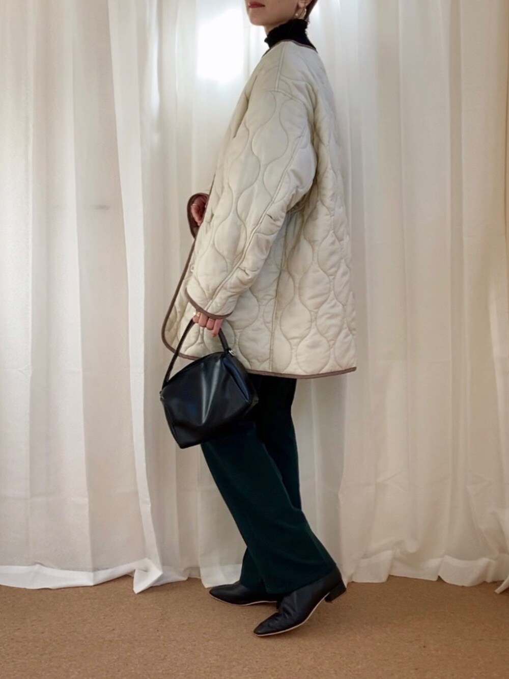 ホワイト系のダウンジャケット/コート、グリーン系のスラックス、ブラック系のショルダーバッグを着用したレディースの冬コーディネートの2枚目の写真