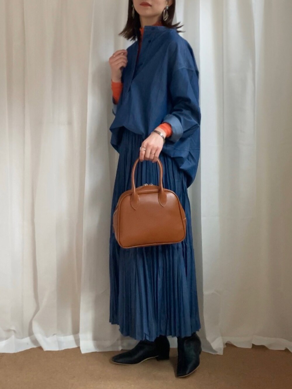 ブルー系のシャツ/ブラウス、ブルー系のデニムスカート、オレンジ系のTシャツ/カットソーを着用したレディースの冬コーディネートの2枚目の写真