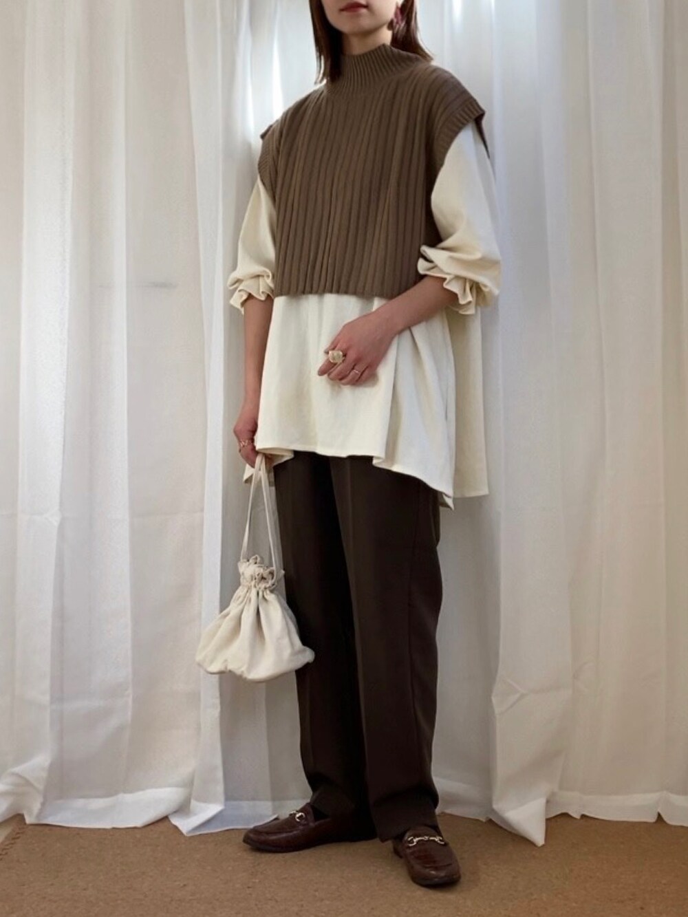 ホワイト系のTシャツ/カットソー、ブラウン系のベスト、ブラウン系のスラックスを着用したレディースの冬コーディネートの2枚目の写真