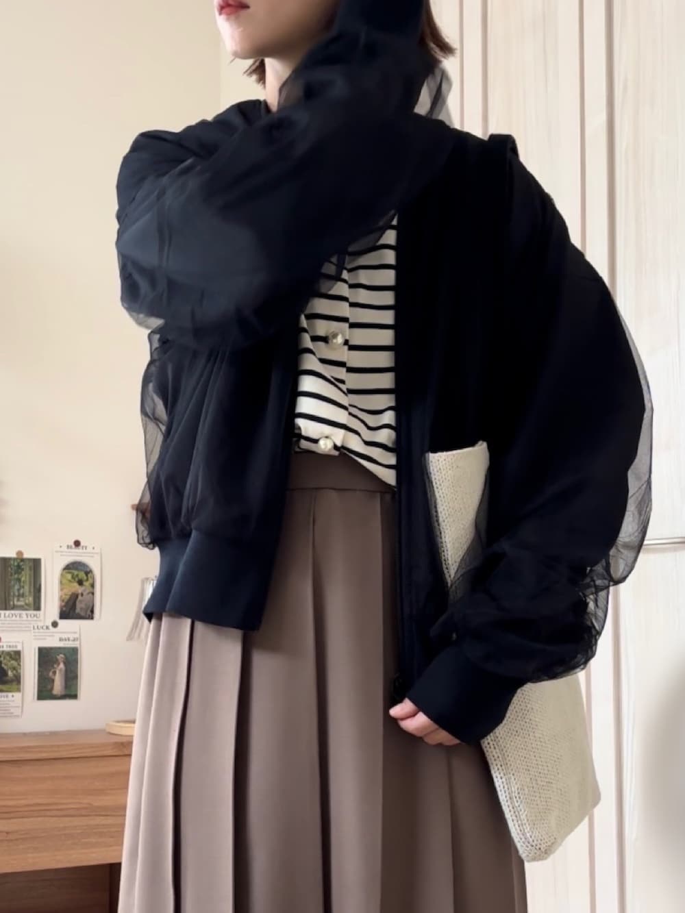 ブラック系のブルゾン、ホワイト系のカーディガン/ボレロ、ブラウン系のローファーを着用したレディースの秋コーディネートの2枚目の写真