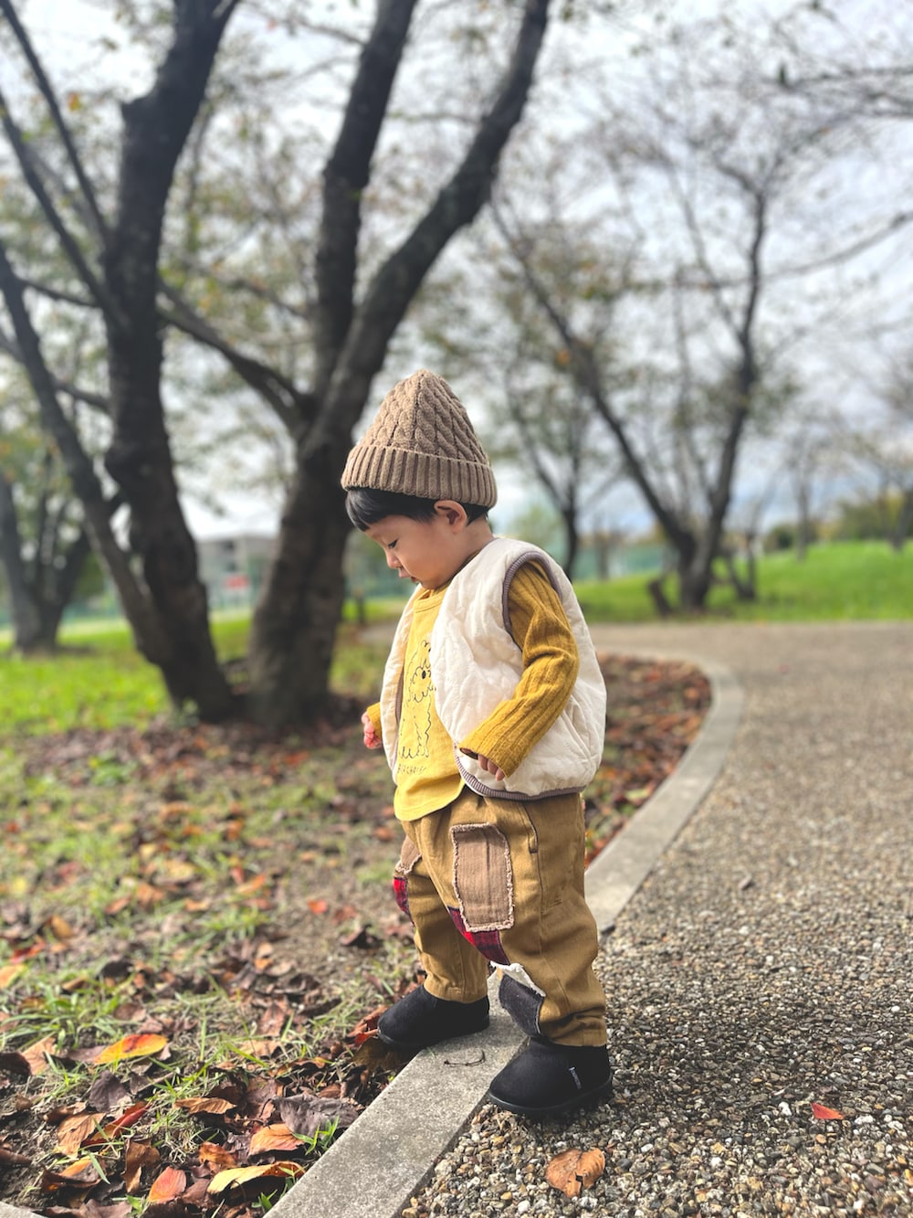 イエロー系のトップス、イエロー系のベスト、ベージュ系のその他パンツを着用したキッズの秋コーディネートの3枚目の写真