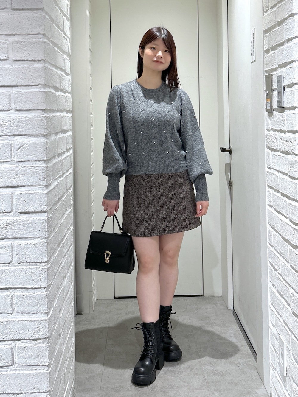 ブラック系のトートバッグ、ブラック系のブーツ、ブラウン系のスカートを着用したレディースの秋コーディネートの9枚目の写真