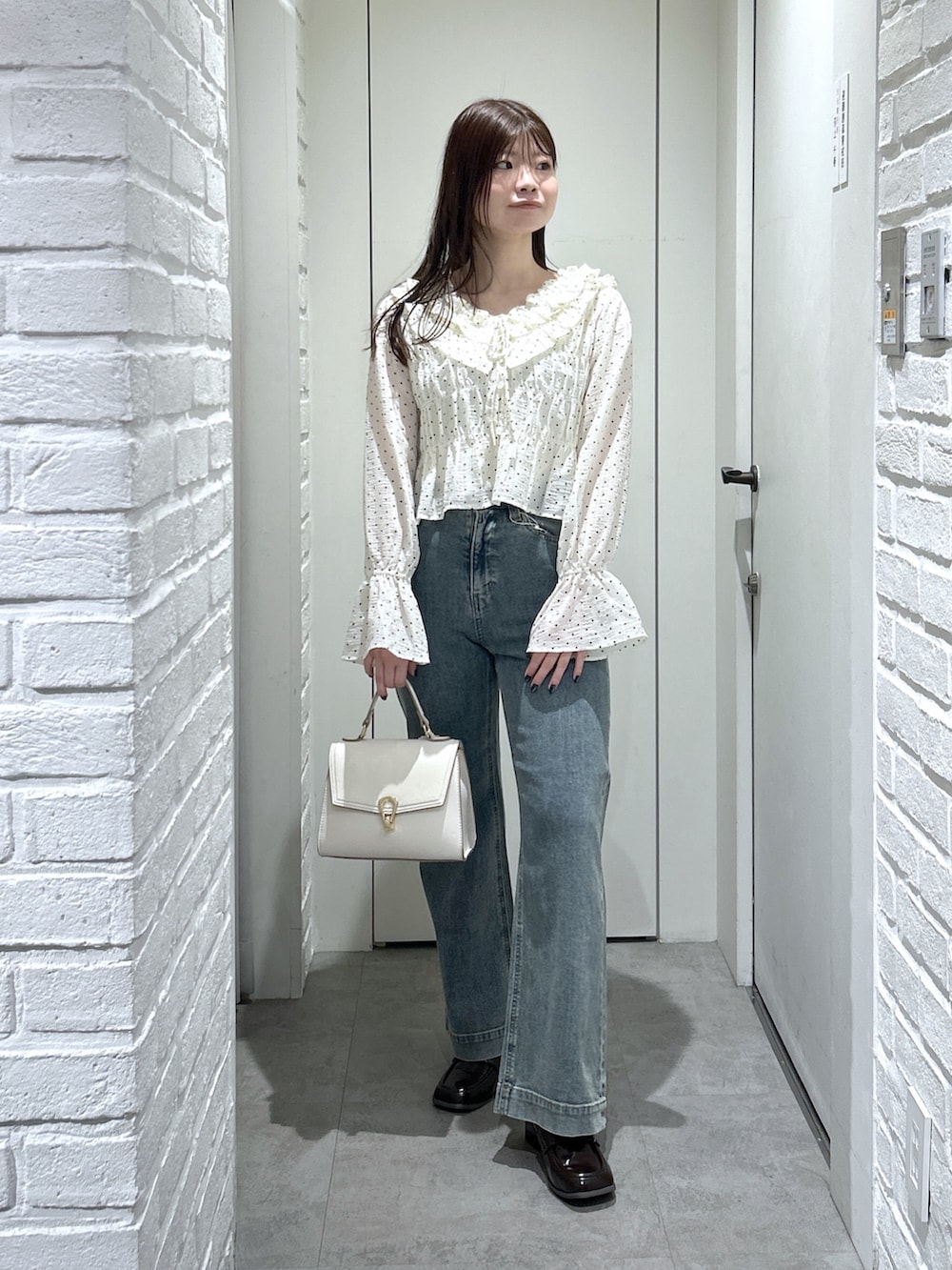 ブラック系のローファー、ブルー系のデニムパンツ、ホワイト系のトートバッグを着用したレディースの冬コーディネートの2枚目の写真