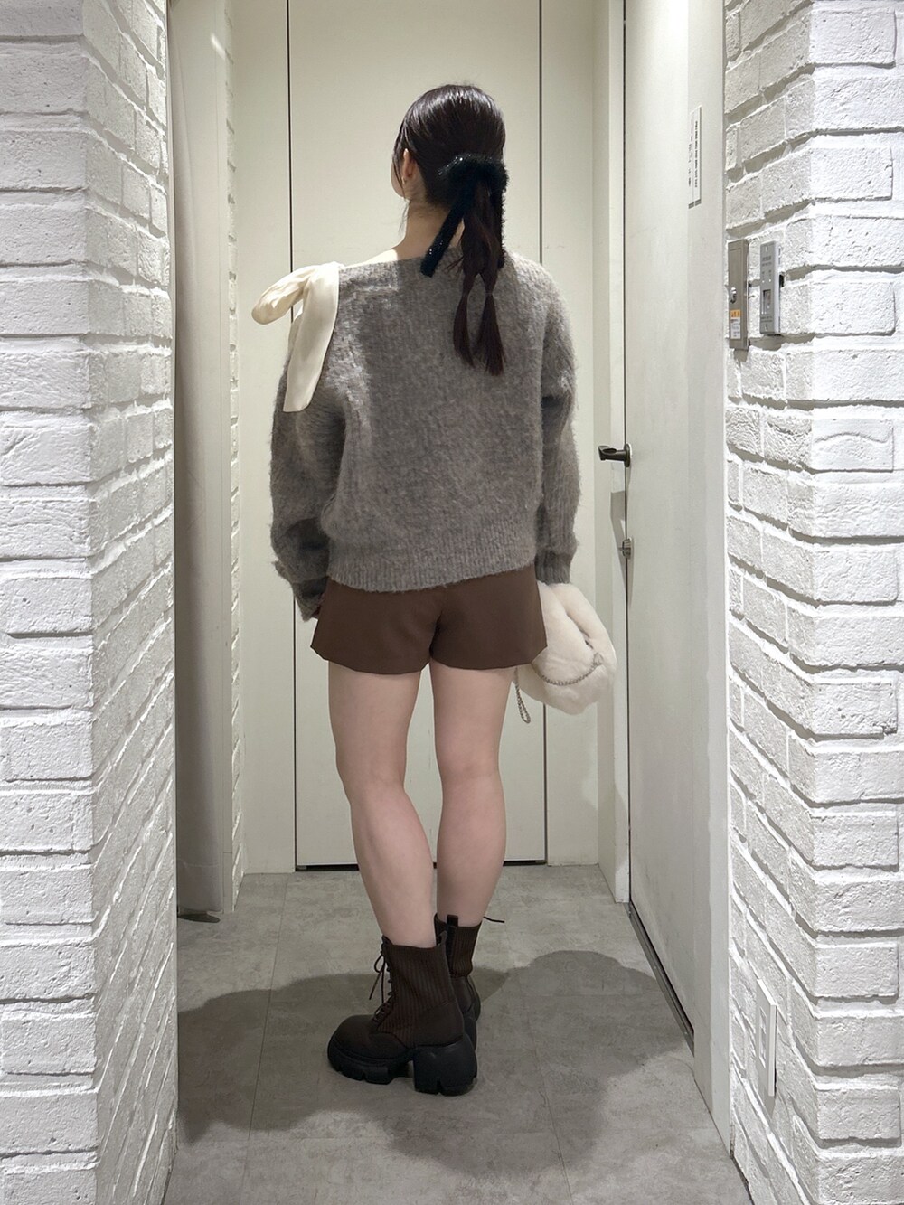 ブラウン系のその他パンツ、ブラウン系のブーツ、ホワイト系のハンドバッグを着用したレディースの冬コーディネートの5枚目の写真