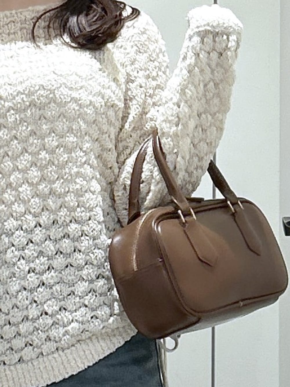 ブルー系のデニムパンツ、ベージュ系のパンプス、ブラウン系のハンドバッグを着用したレディースの冬コーディネートの3枚目の写真