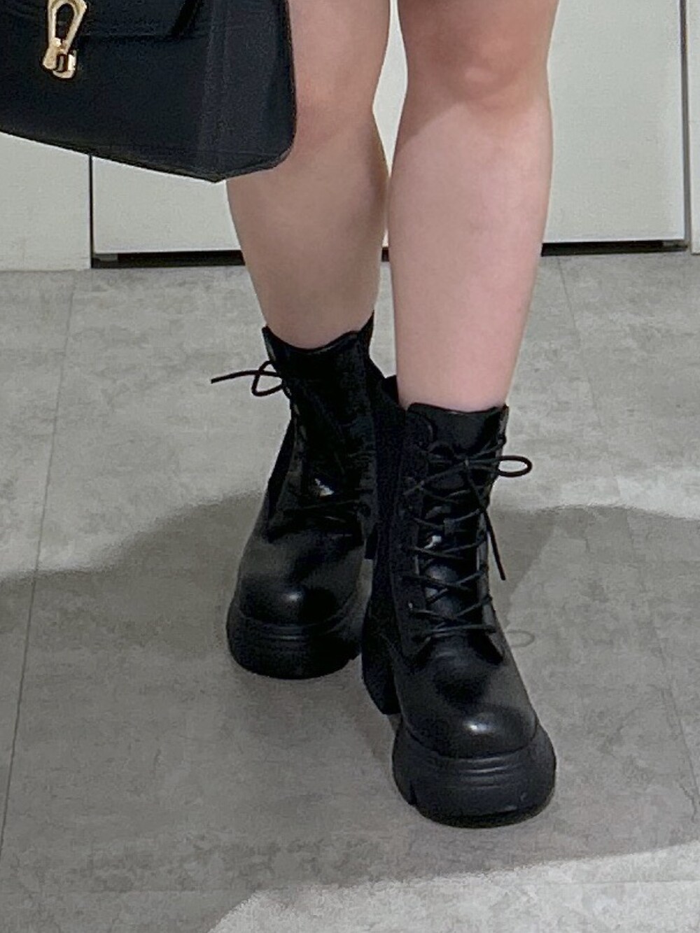 ブラック系のトートバッグ、ブラック系のブーツ、ブラウン系のスカートを着用したレディースの秋コーディネートの7枚目の写真