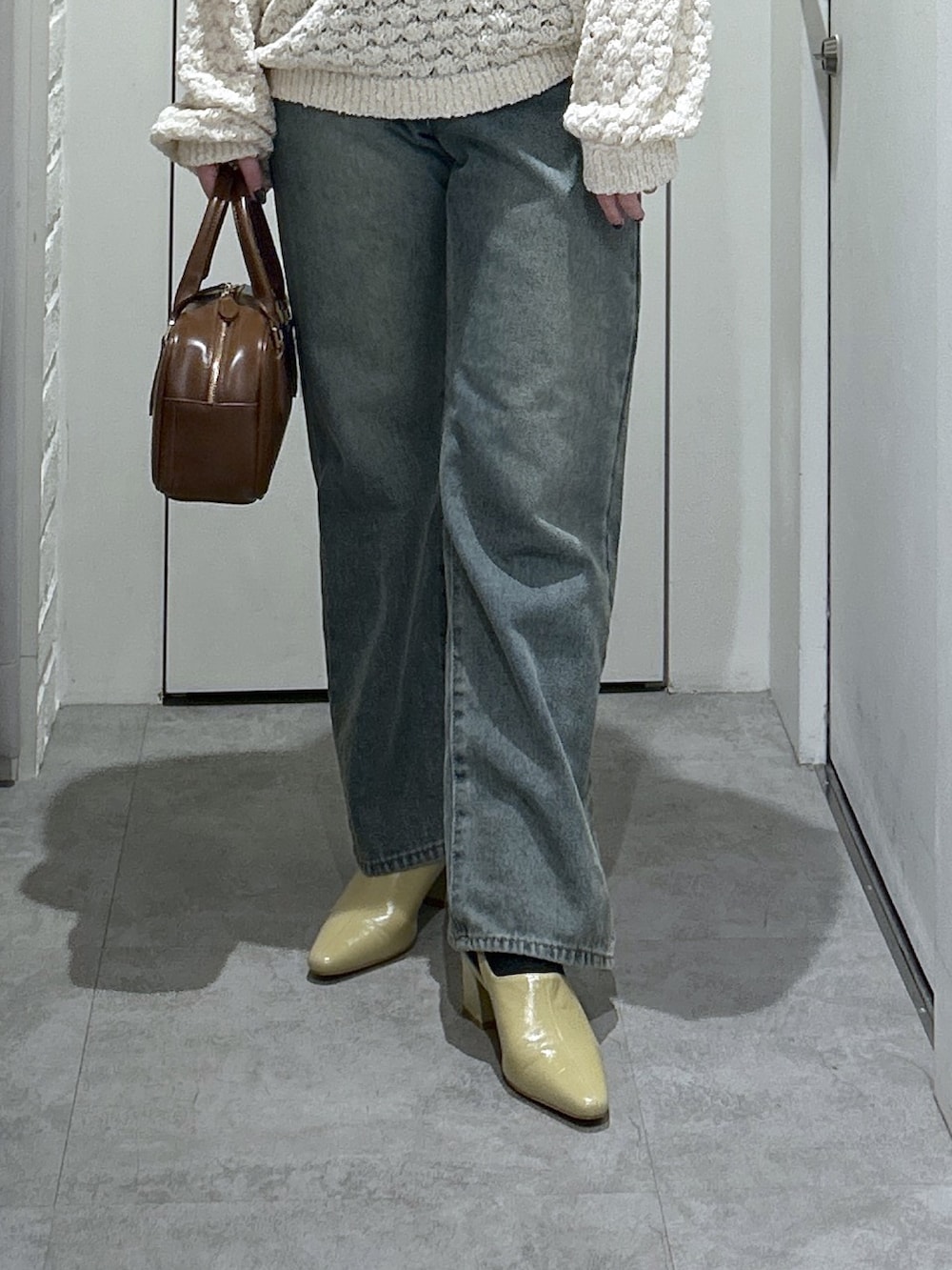 ブルー系のデニムパンツ、ベージュ系のパンプス、ブラウン系のハンドバッグを着用したレディースの冬コーディネートの4枚目の写真