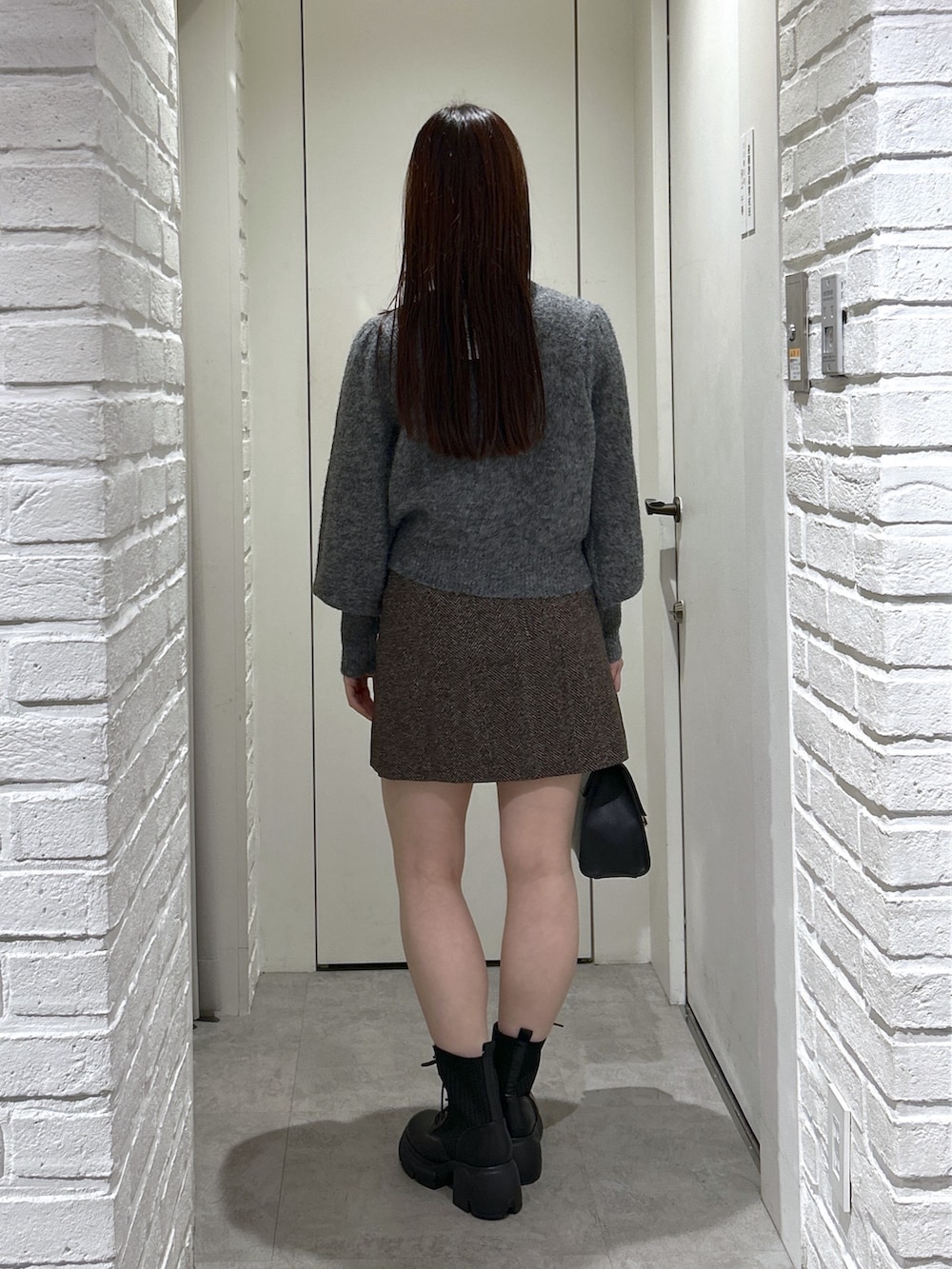 ブラック系のトートバッグ、ブラック系のブーツ、ブラウン系のスカートを着用したレディースの秋コーディネートの4枚目の写真