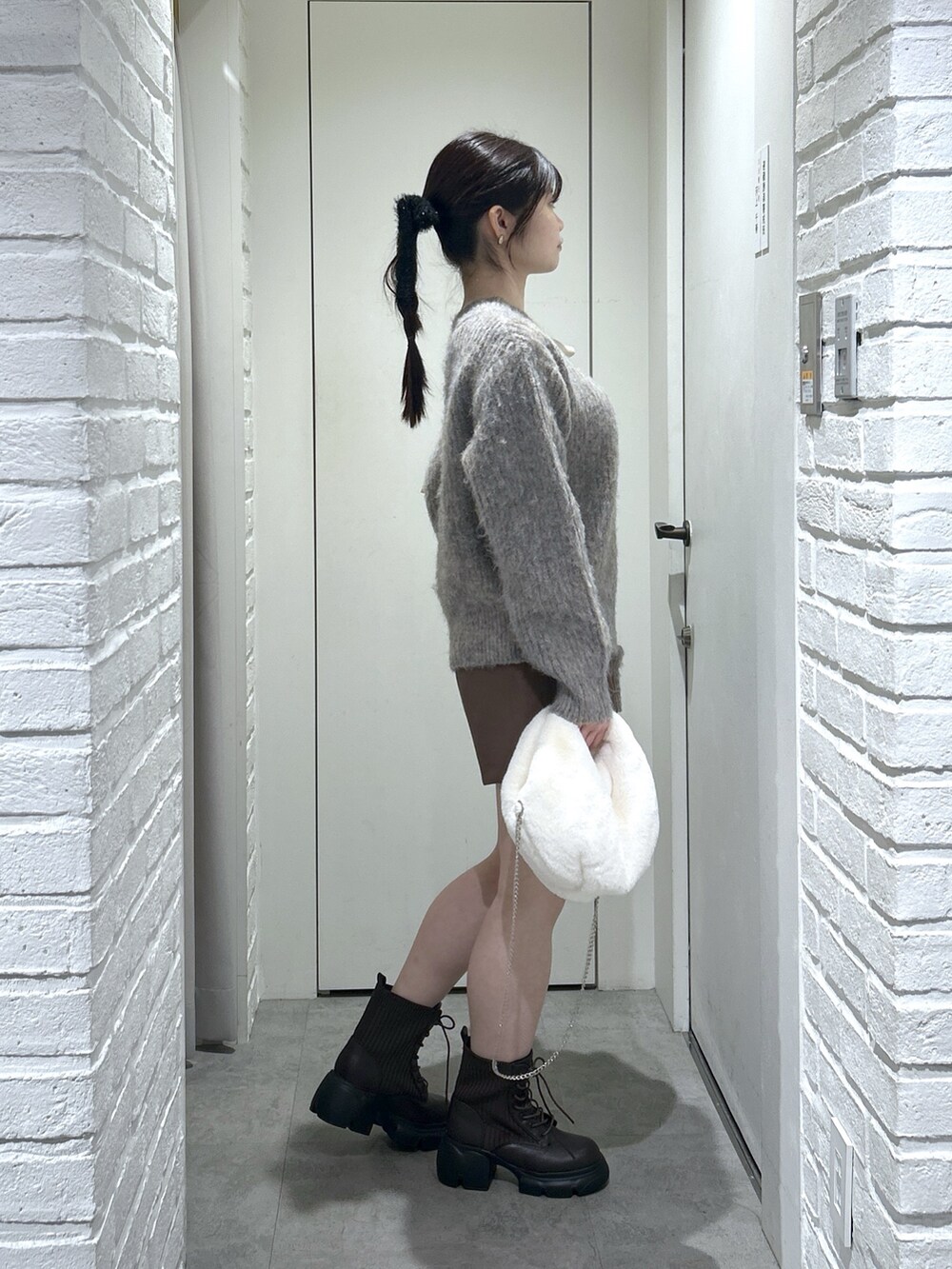 ブラウン系のその他パンツ、ブラウン系のブーツ、ホワイト系のハンドバッグを着用したレディースの冬コーディネートの4枚目の写真
