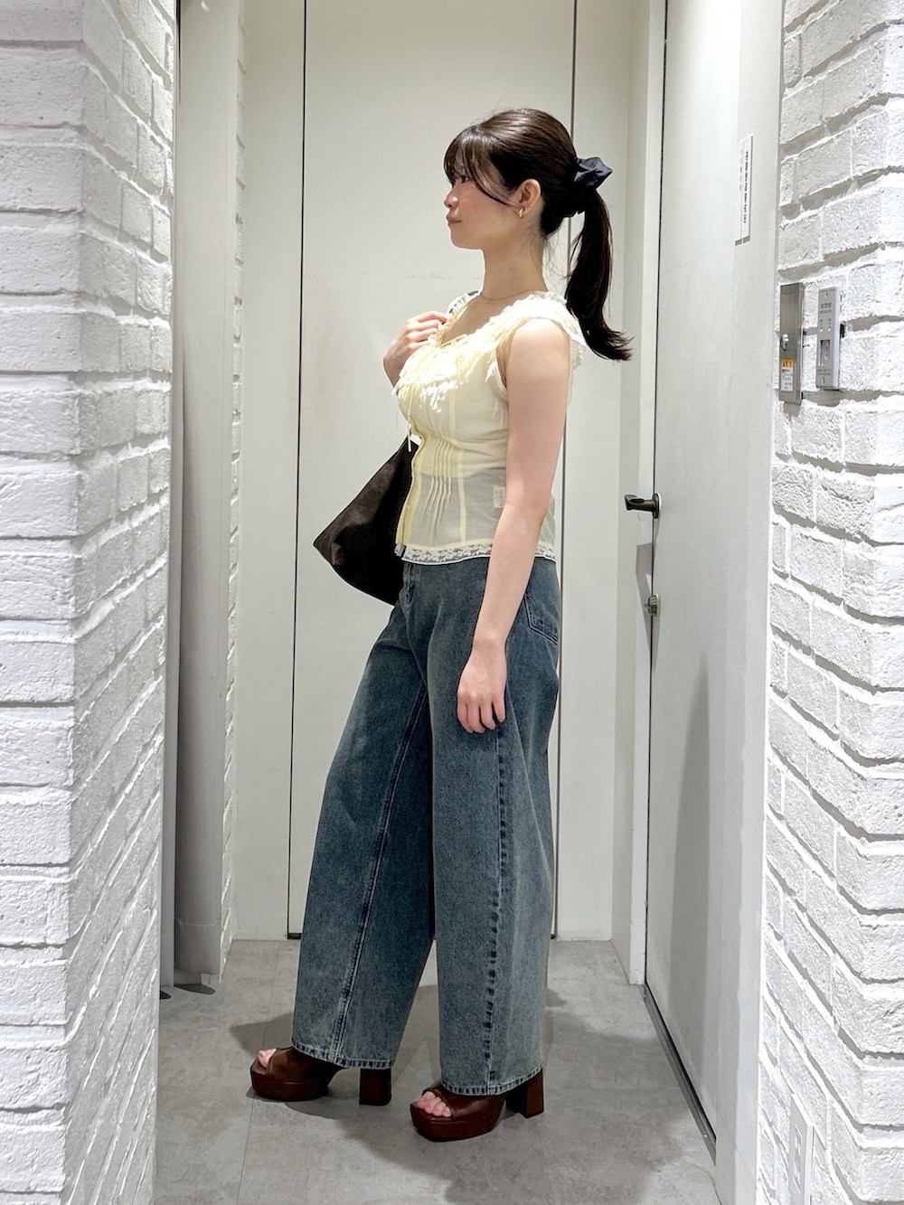 ブラウン系のサンダル、ブルー系のデニムパンツ、イエロー系のシャツ/ブラウスを着用したレディースの夏コーディネートの3枚目の写真