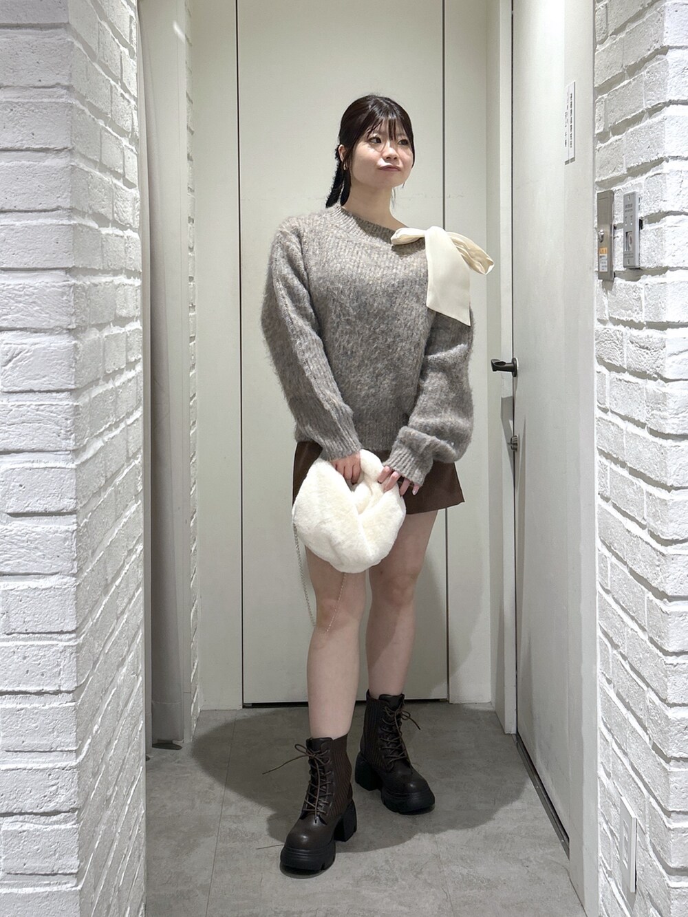 ブラウン系のその他パンツ、ブラウン系のブーツ、ホワイト系のハンドバッグを着用したレディースの冬コーディネートの2枚目の写真