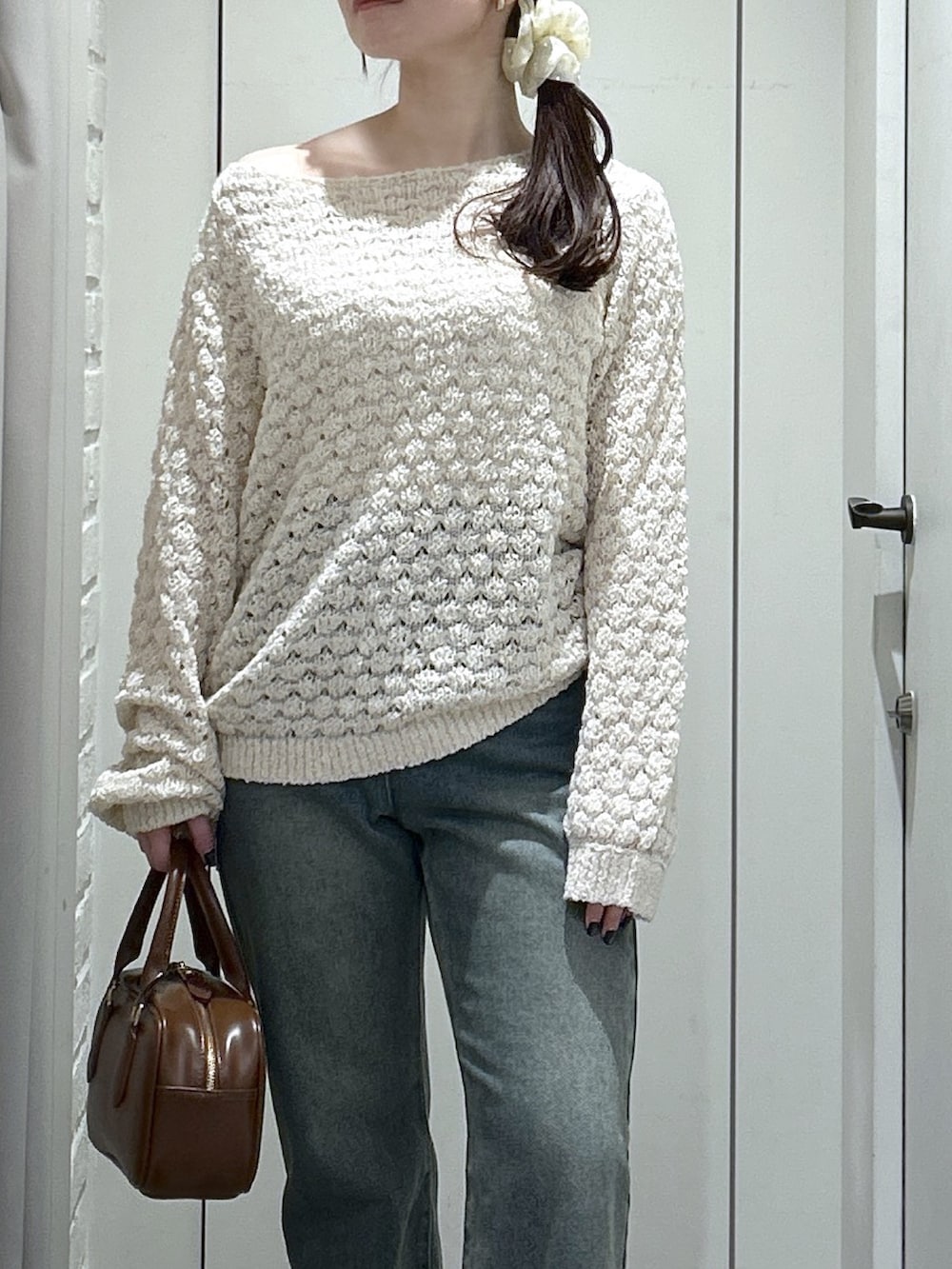 ブルー系のデニムパンツ、ベージュ系のパンプス、ブラウン系のハンドバッグを着用したレディースの冬コーディネートの2枚目の写真