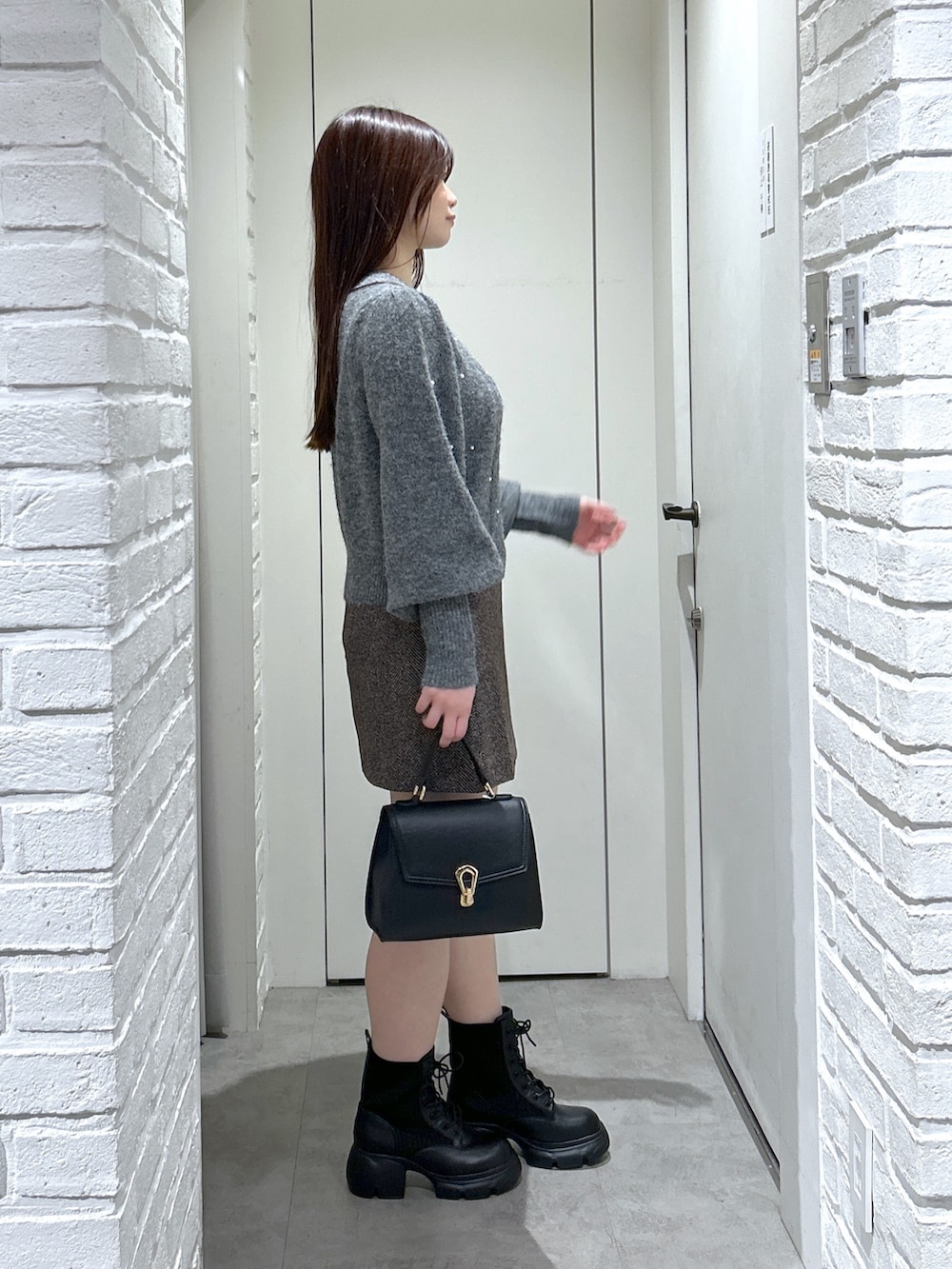 ブラック系のトートバッグ、ブラック系のブーツ、ブラウン系のスカートを着用したレディースの秋コーディネートの3枚目の写真