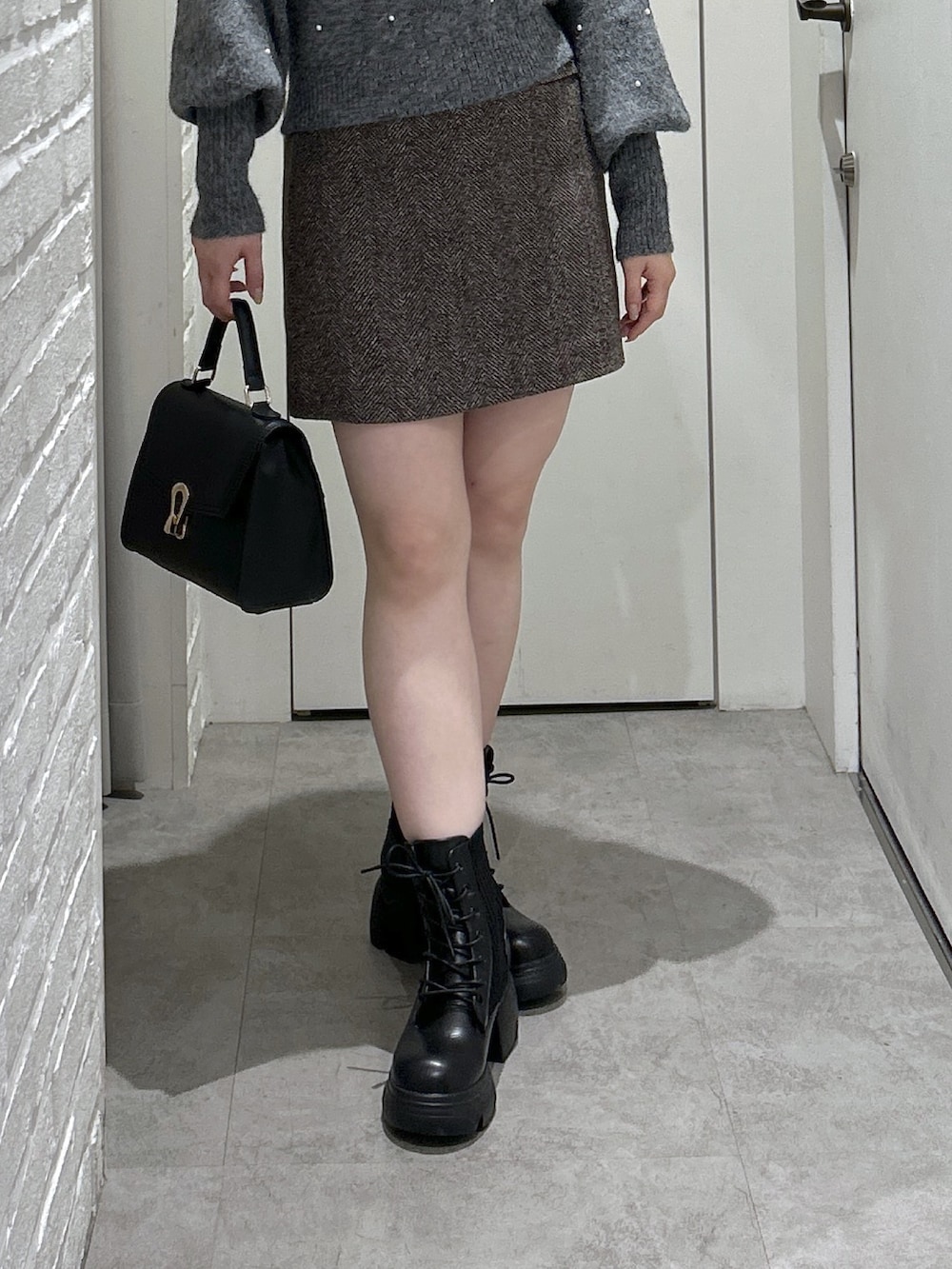 ブラック系のトートバッグ、ブラック系のブーツ、ブラウン系のスカートを着用したレディースの秋コーディネートの6枚目の写真