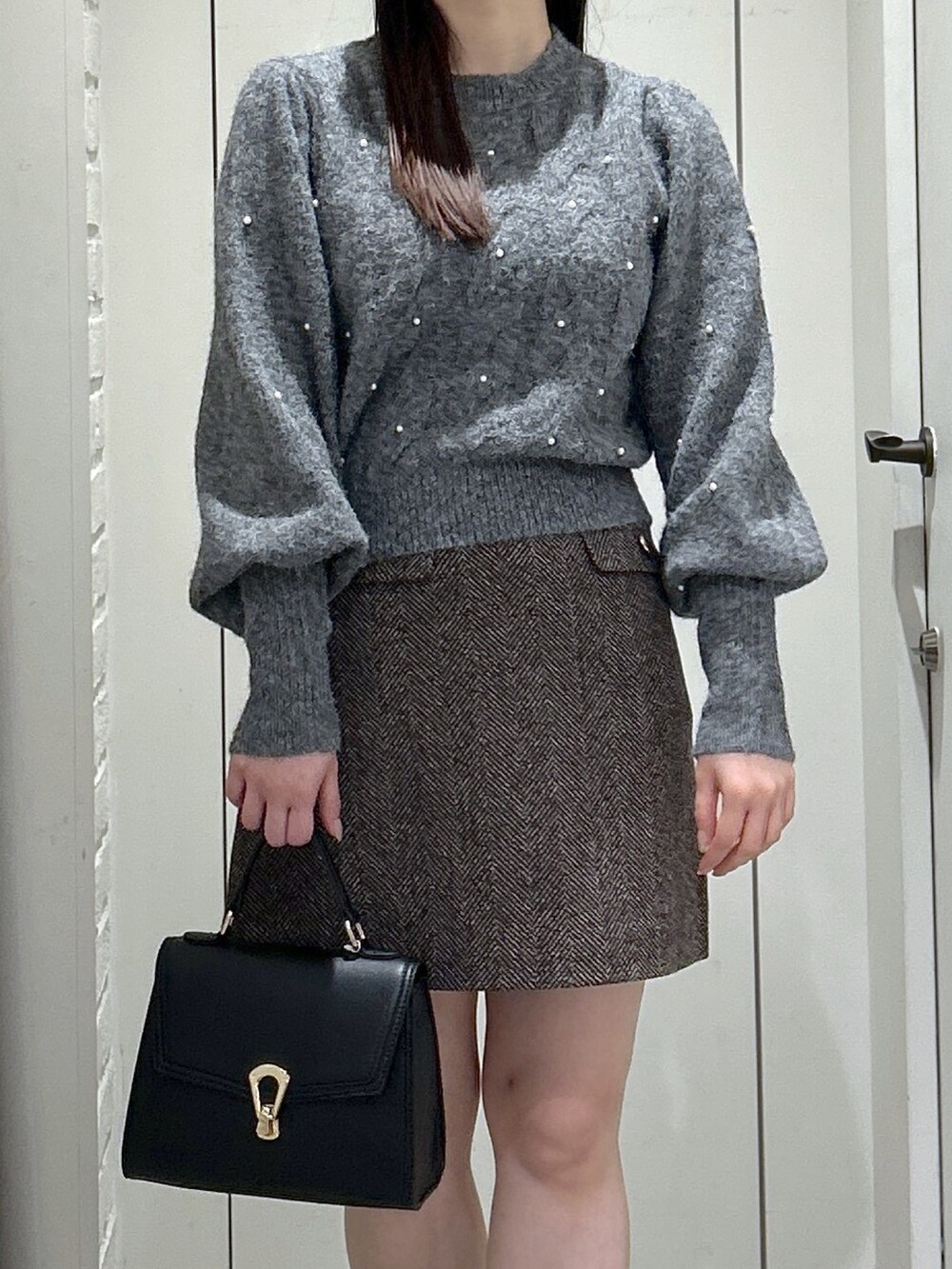 ブラック系のトートバッグ、ブラック系のブーツ、ブラウン系のスカートを着用したレディースの秋コーディネートの8枚目の写真