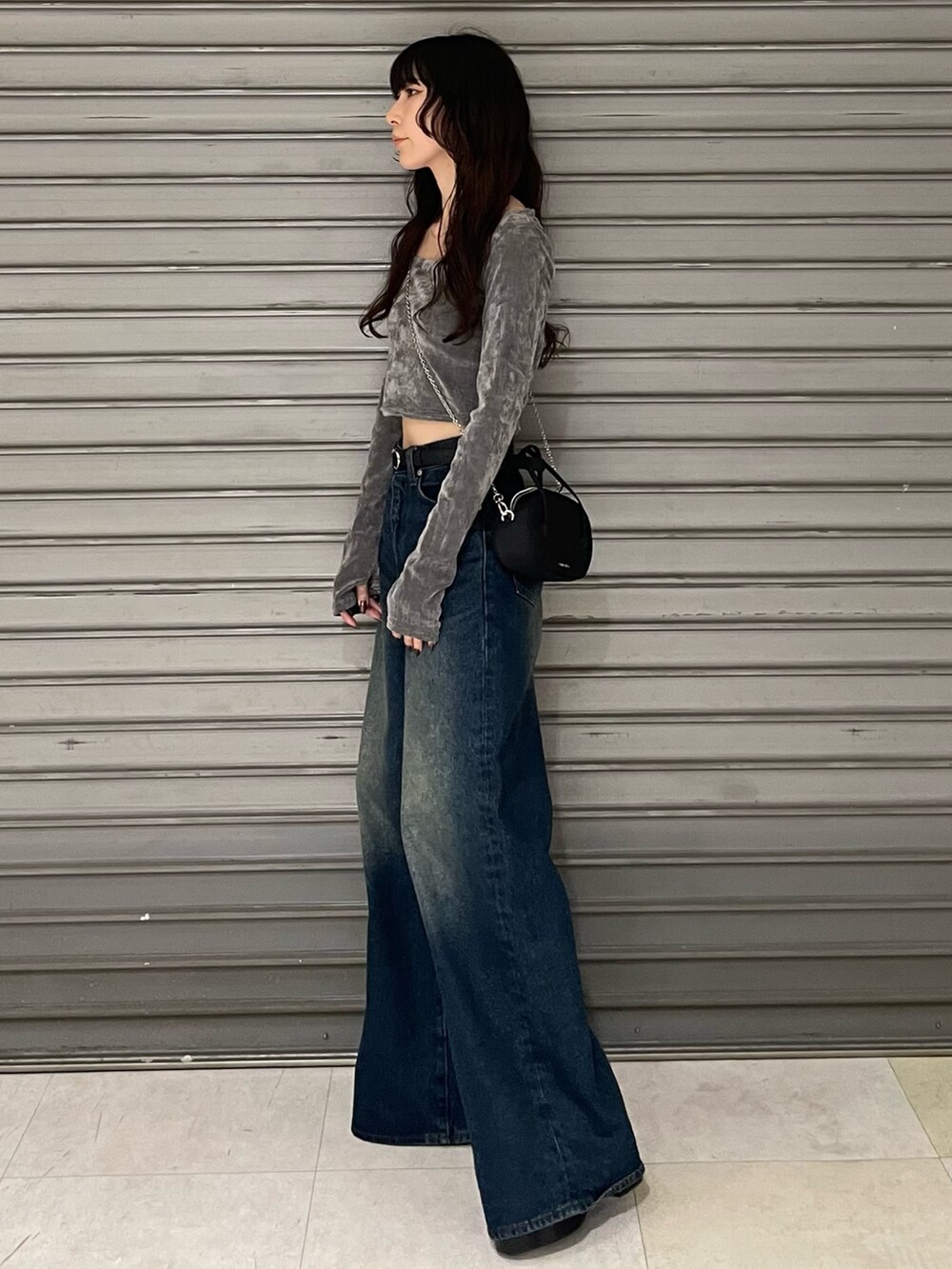 グレー系のTシャツ/カットソー、ブルー系のデニムパンツ、ブラック系のブーツを着用したレディースの秋コーディネートの2枚目の写真