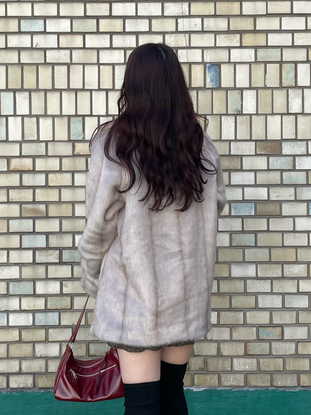 ブラック系のブーツ、レッド系のハンドバッグ、ブラック系のニット/セーターを着用したレディースの秋コーディネートの6枚目の写真