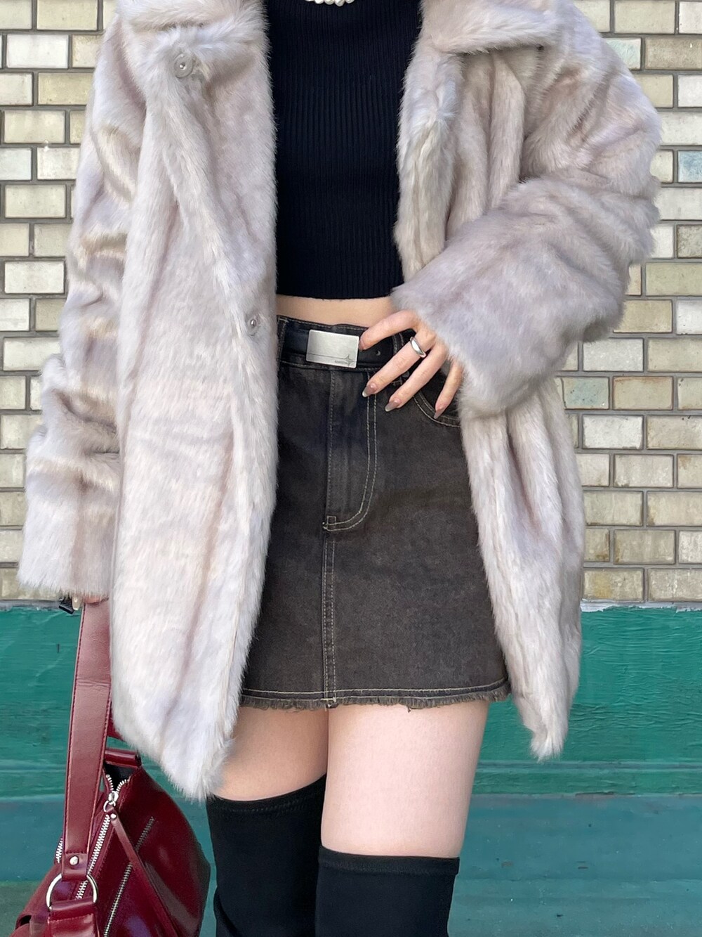 ブラック系のブーツ、レッド系のハンドバッグ、ブラック系のニット/セーターを着用したレディースの秋コーディネートの8枚目の写真