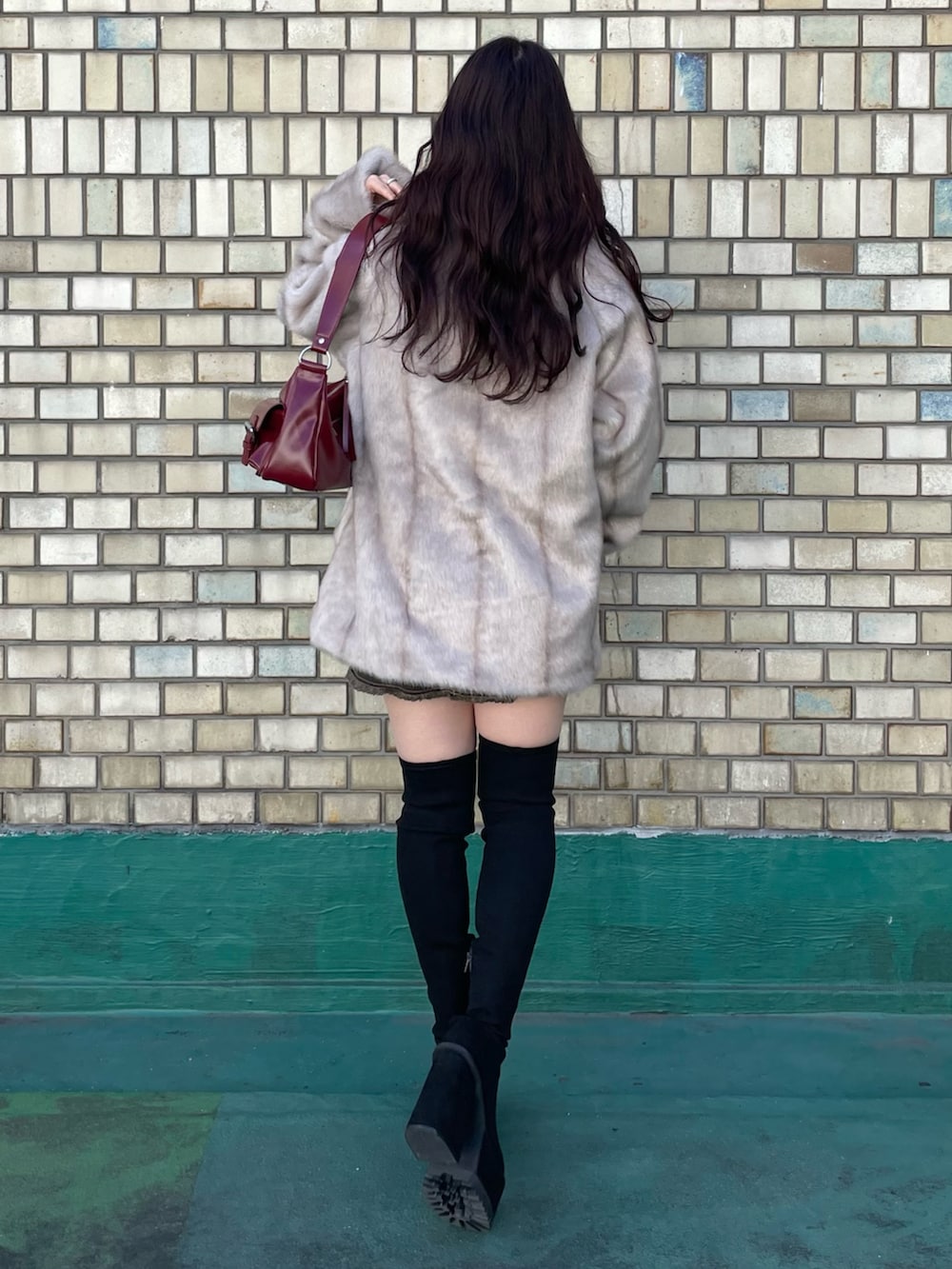 ブラック系のブーツ、レッド系のハンドバッグ、ブラック系のニット/セーターを着用したレディースの秋コーディネートの3枚目の写真