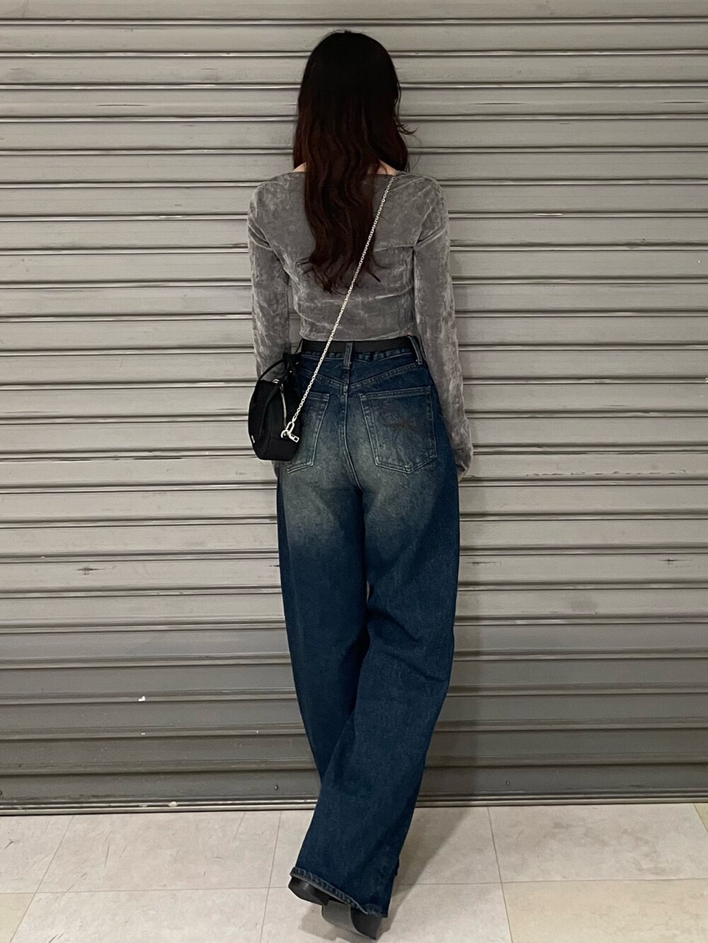 グレー系のTシャツ/カットソー、ブルー系のデニムパンツ、ブラック系のブーツを着用したレディースの秋コーディネートの3枚目の写真