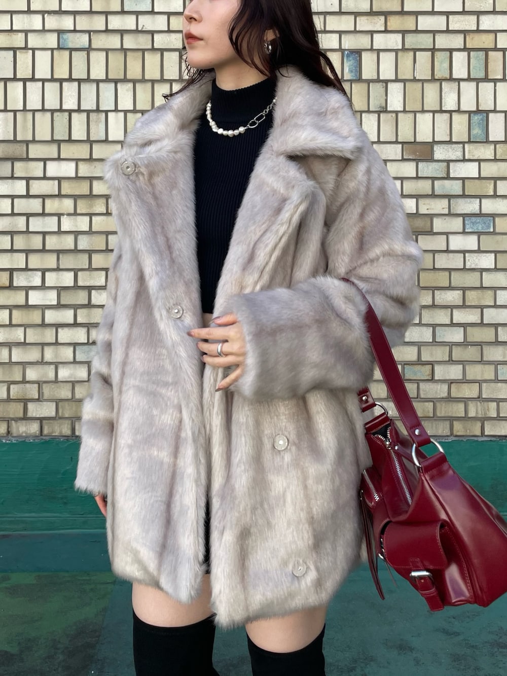 ブラック系のブーツ、レッド系のハンドバッグ、ブラック系のニット/セーターを着用したレディースの秋コーディネートの5枚目の写真