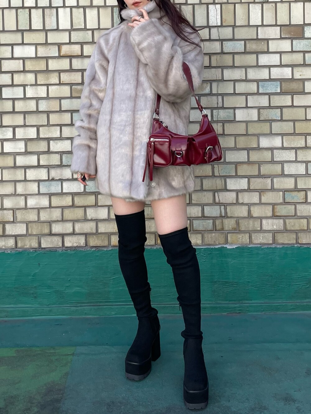 ブラック系のブーツ、レッド系のハンドバッグ、ブラック系のニット/セーターを着用したレディースの秋コーディネートの7枚目の写真