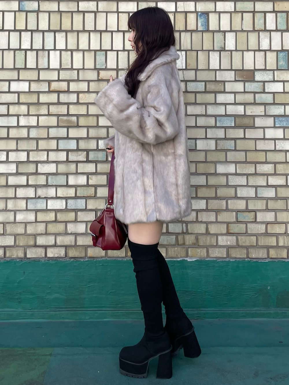 ブラック系のブーツ、レッド系のハンドバッグ、ブラック系のニット/セーターを着用したレディースの秋コーディネートの2枚目の写真