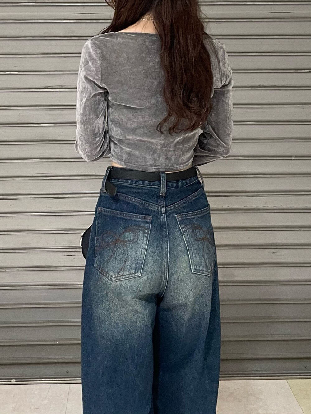 グレー系のTシャツ/カットソー、ブルー系のデニムパンツ、ブラック系のブーツを着用したレディースの秋コーディネートの6枚目の写真