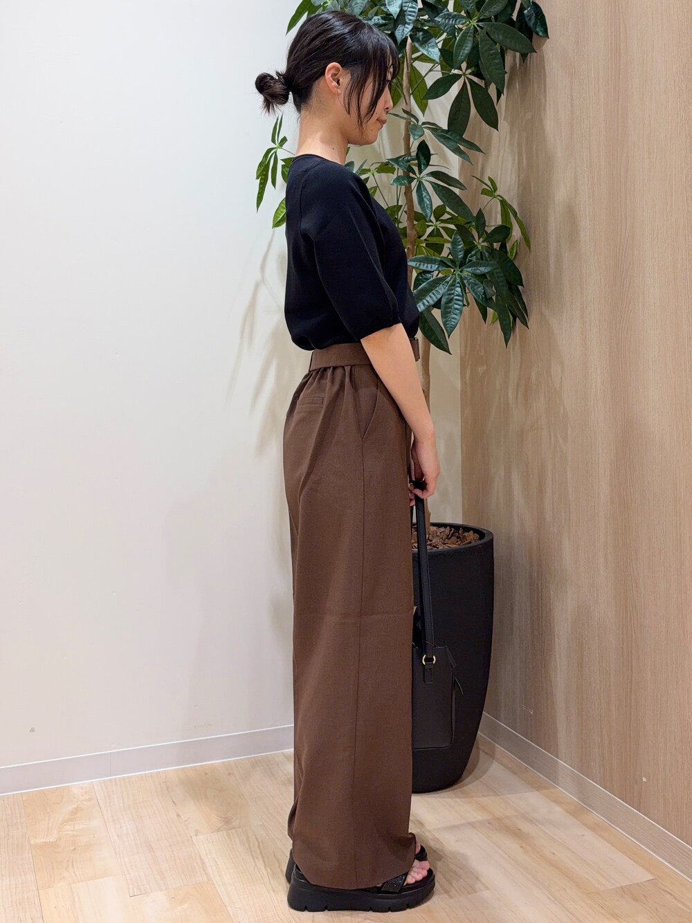 ブラック系のニット/セーター、ブラウン系のその他パンツ、ブラック系のショルダーバッグを着用したレディースの夏コーディネートの2枚目の写真