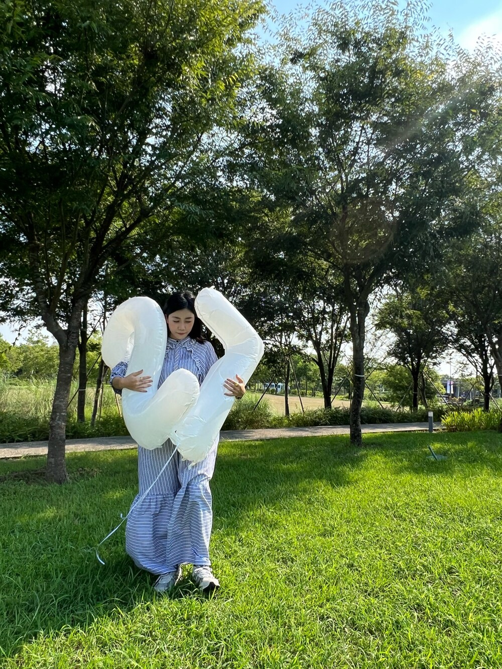 ホワイト系のワンピース、ベージュ系のスニーカーを着用したレディースの夏コーディネートの2枚目の写真