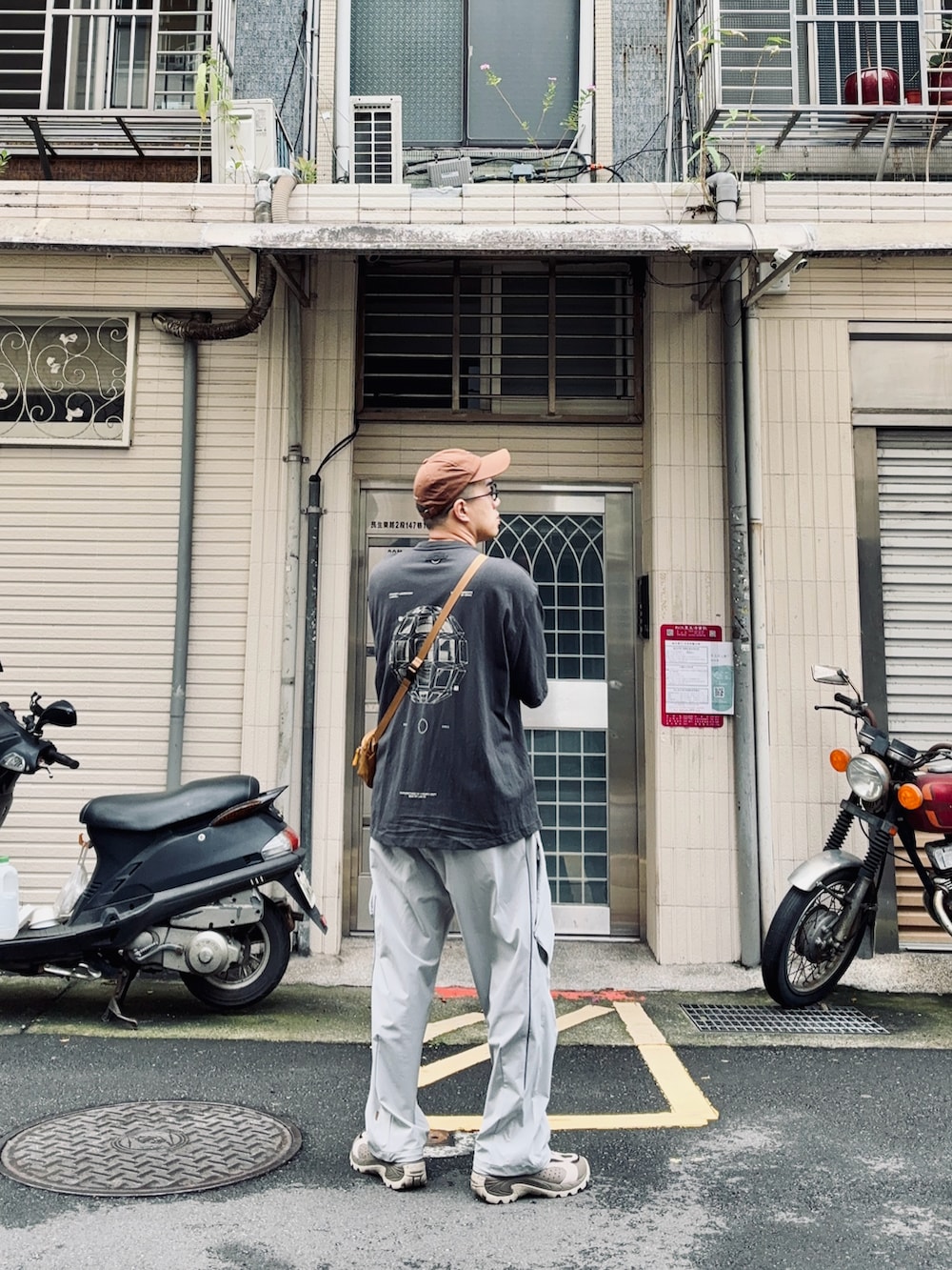 ブラック系のTシャツ/カットソー、ブラウン系のショルダーバッグ、ベージュ系のシューズを着用したメンズの夏コーディネートの2枚目の写真