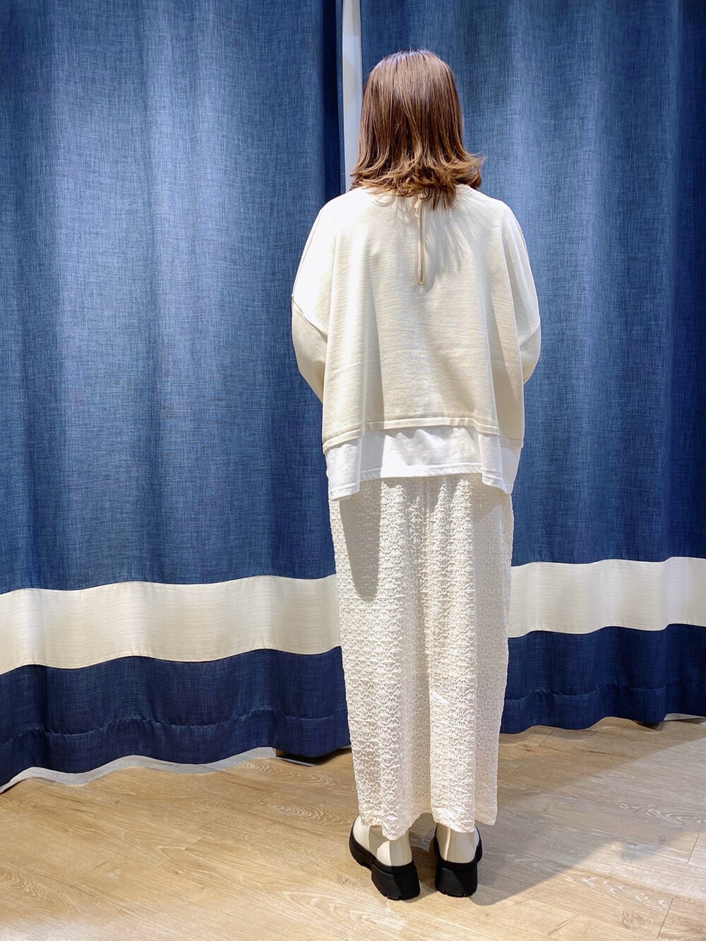 ホワイト系のニット/セーター、ホワイト系のスカート、ホワイト系のブーツを着用したレディースの冬コーディネートの2枚目の写真