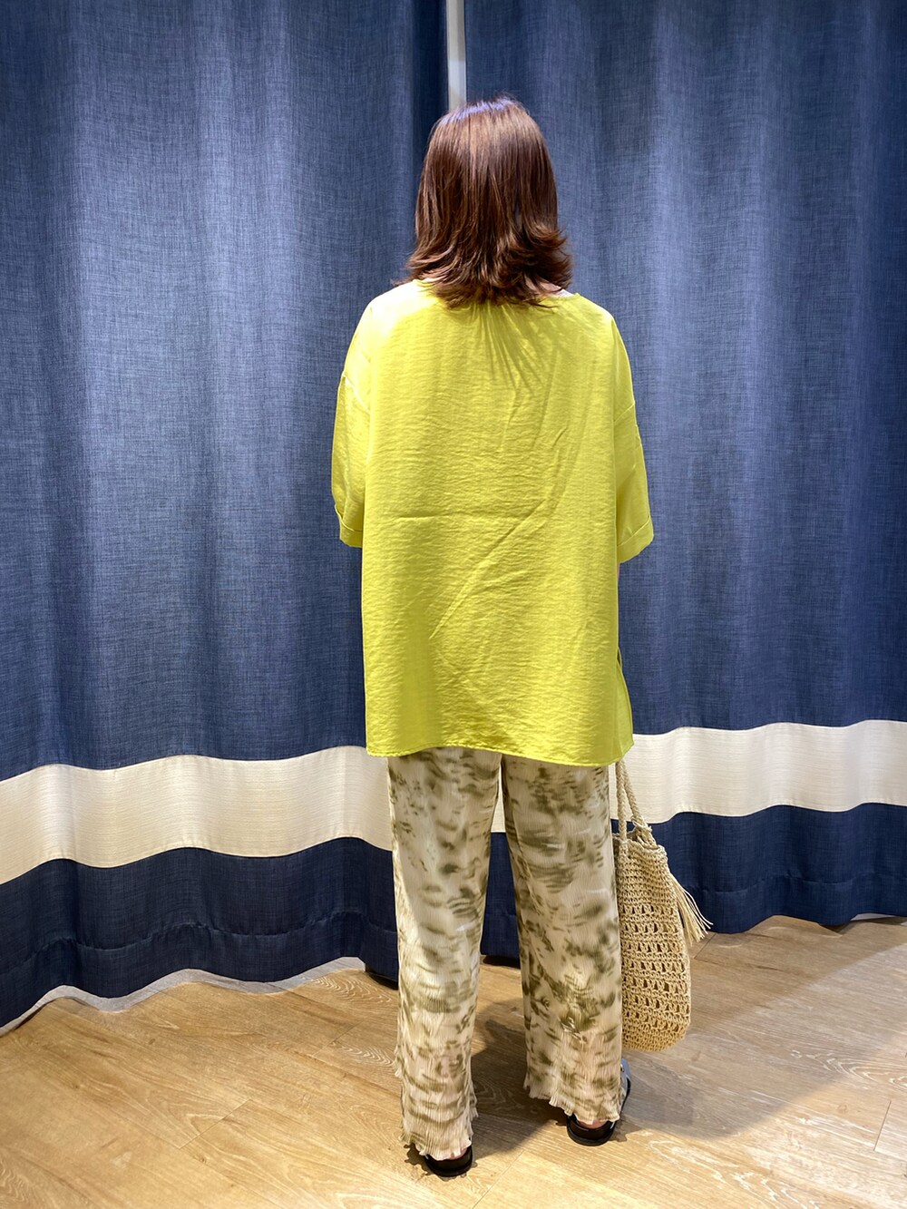 イエロー系のトップス、グリーン系のその他パンツ、ベージュ系のハンドバッグを着用したレディースの夏コーディネートの2枚目の写真