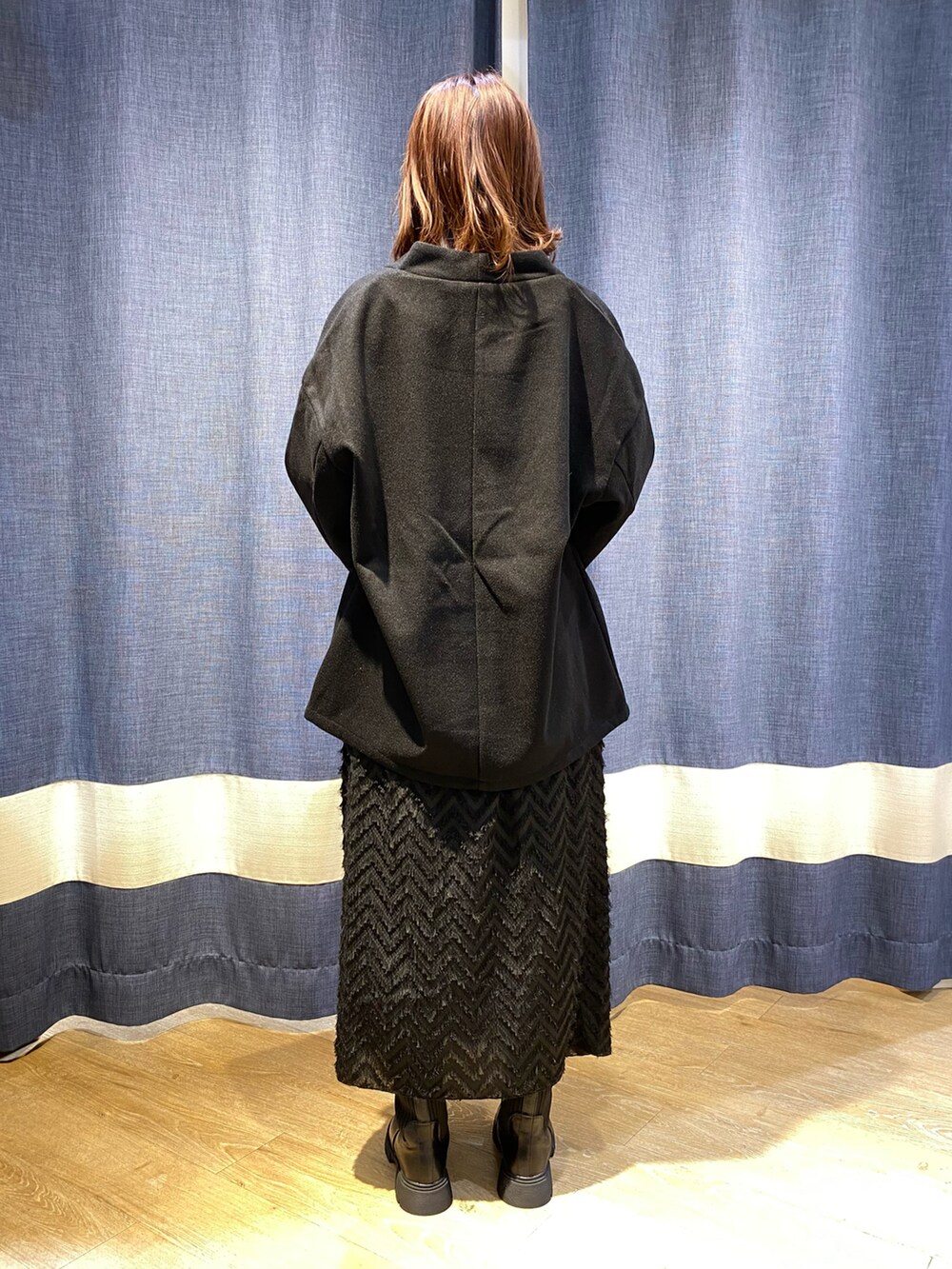 ブラック系のその他アウター、ブルー系のニット/セーター、ブラック系のスカートを着用したレディースの秋コーディネートの2枚目の写真