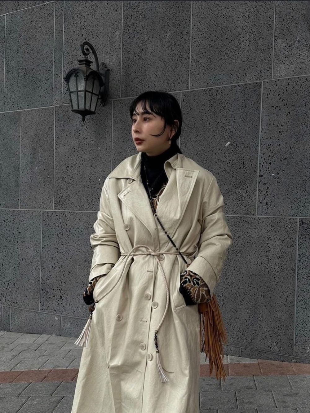 ホワイト系のトレンチコート、ベージュ系のベストを着用したレディースの秋コーディネートの2枚目の写真
