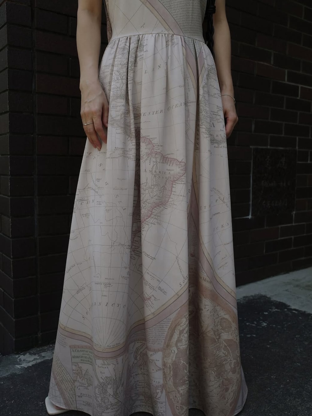 ベージュ系のワンピース、ホワイト系のサンダル、ブラック系のショルダーバッグを着用したレディースの夏コーディネートの3枚目の写真