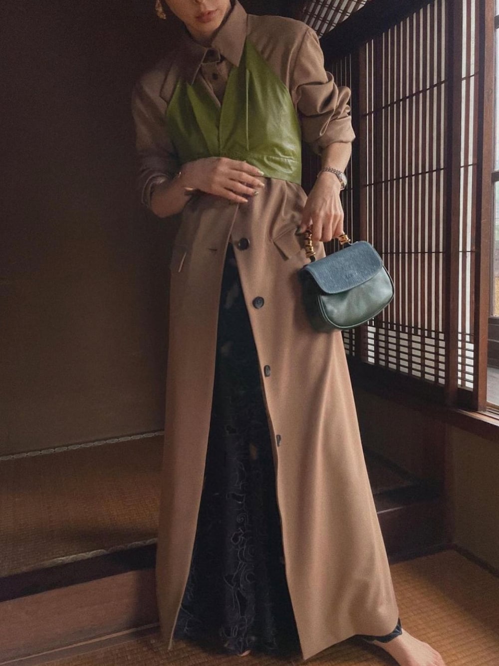 ブラウン系のワンピース、ブラック系のスカート、ゴールド系のピアス（両耳用）を着用したレディースの冬コーディネートの2枚目の写真