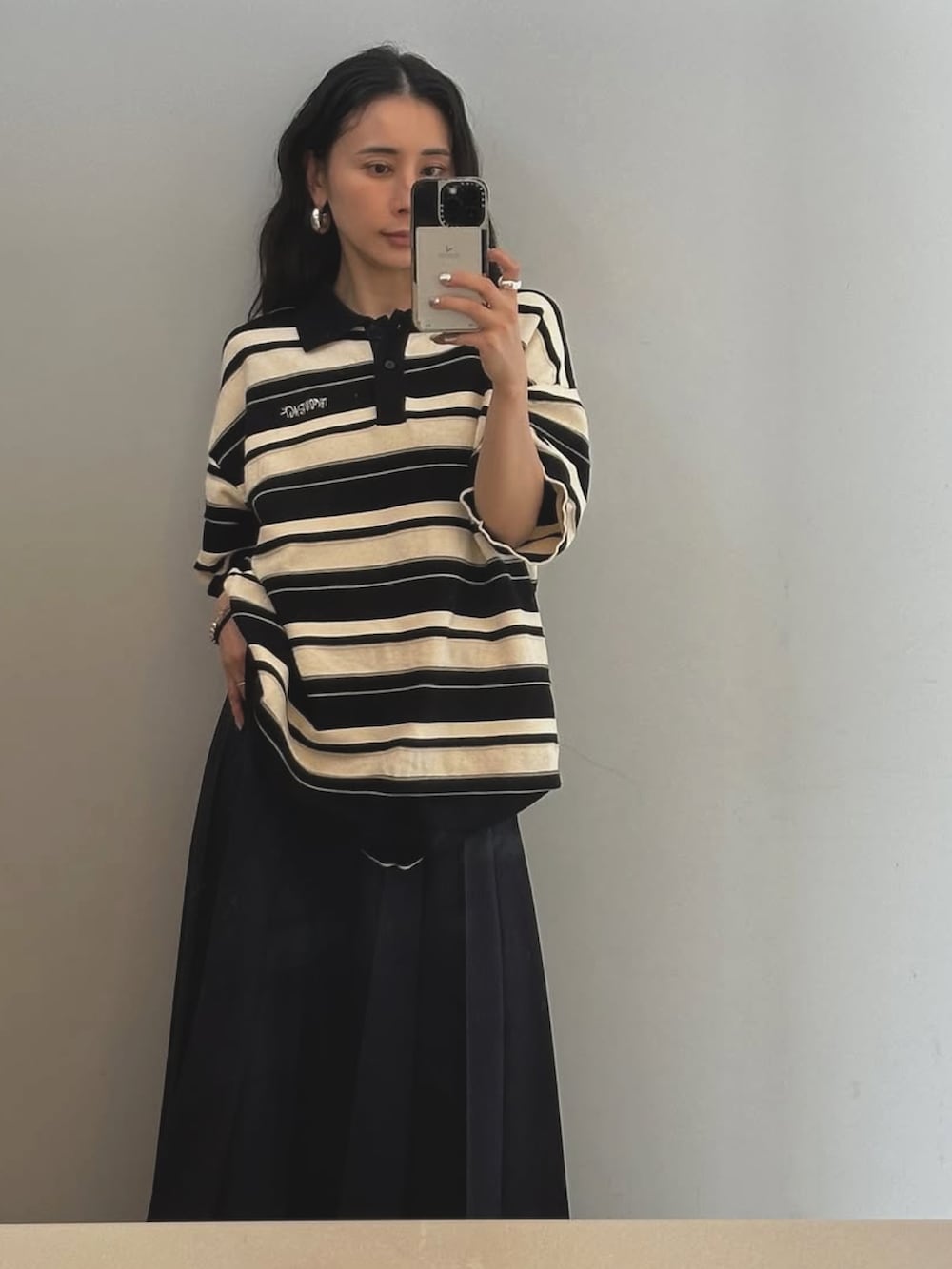 オレンジ系のポロシャツを着用したレディースの秋コーディネートの2枚目の写真