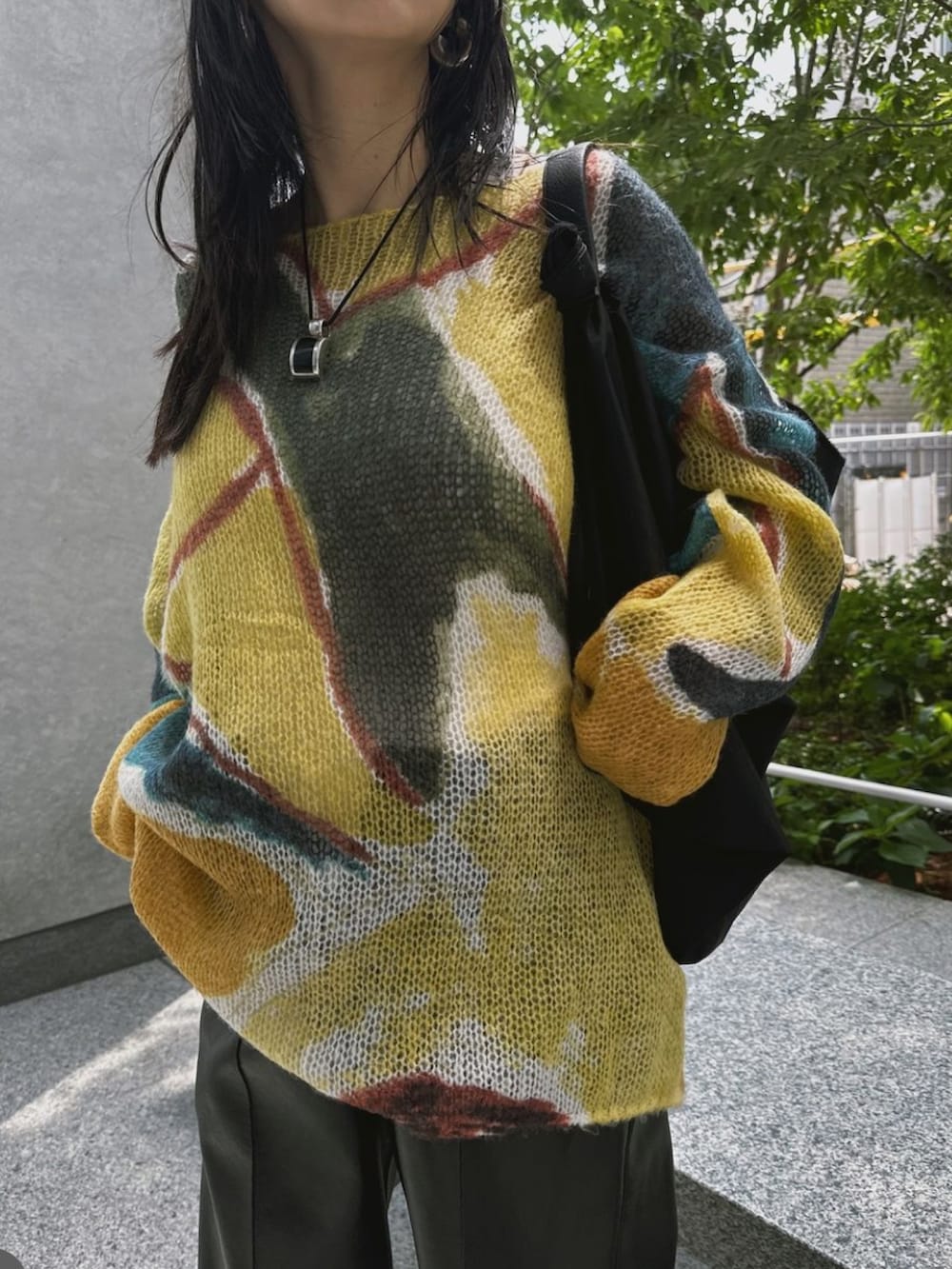 イエロー系のニット/セーター、ブラック系のパンツを着用したレディースの秋コーディネートの3枚目の写真